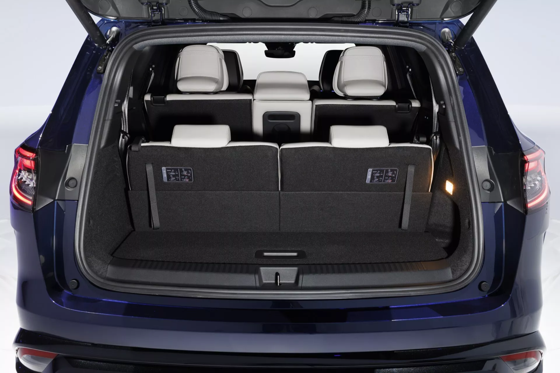 Renault Espace VI 2023 montrant la section arrière avec le coffre ouvert, vue arrière directe dans le compartiment à bagages propre et bien éclairé mettant en évidence la capacité de chargement et les sièges arrière de troisième rangée pliables 50/50 dans un intérieur possiblement beige ou gris