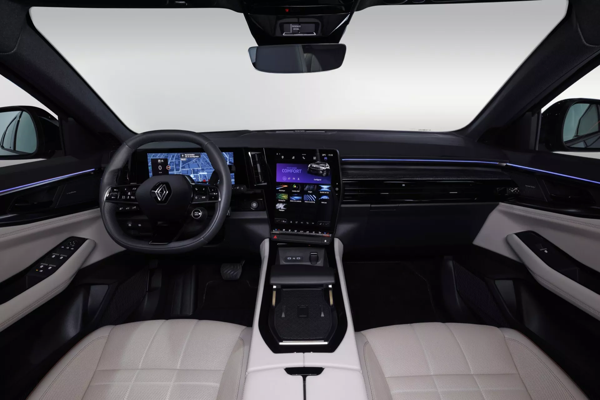 Vue intérieure du Renault Espace VI 2023 depuis le siège arrière central montrant le Volant avec Commandes, le Tableau de Bord Numérique, le Système Infotainment Tactile, l'Éclairage Ambiant, les Sièges en Cuir Bicolore, le Sélecteur de Vitesse Moderne, les Matériaux de Haute Qualité et les Éléments de Design Élégants