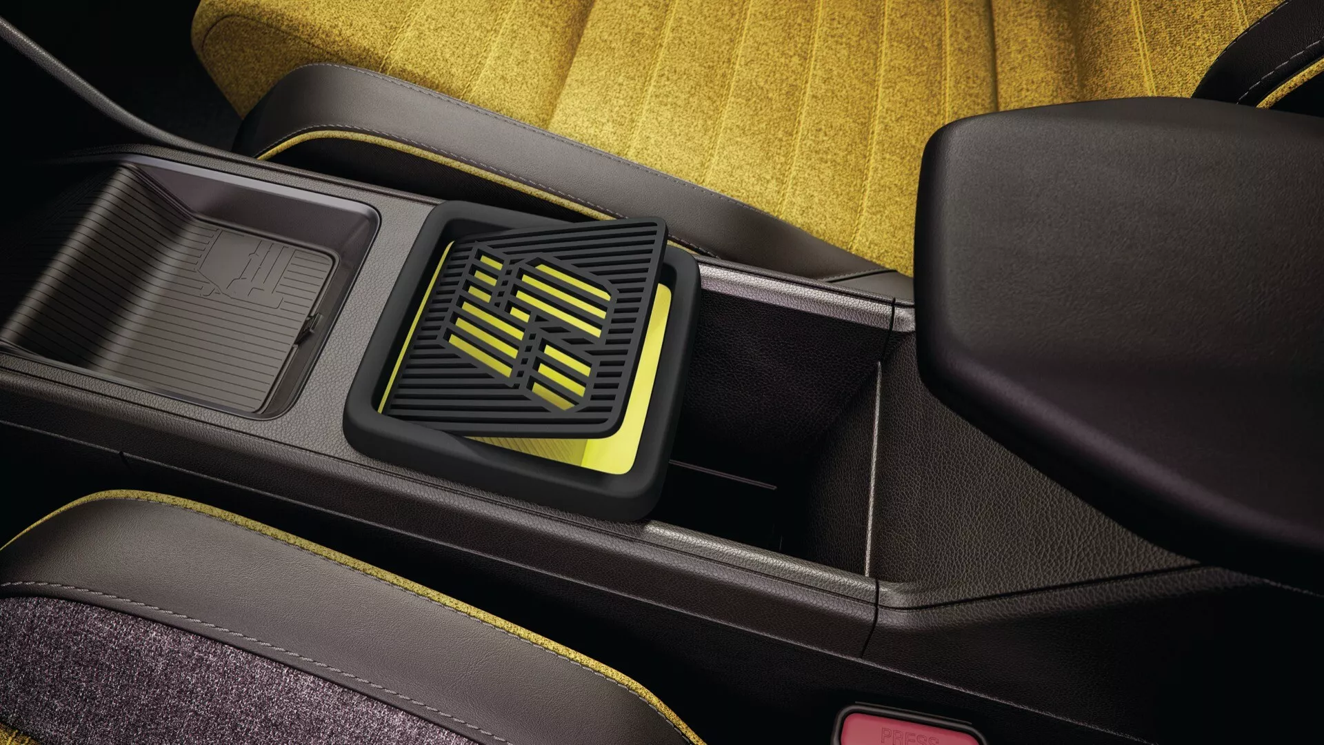 Détail intérieur du Renault R5 2024 montrant la zone de la console centrale, comprenant un compartiment de rangement ouvert avec tapis texturé, système de ventilation adjacent au design géométrique moderne avec des accents jaune-vert sur fond noir, textures contrastées, et un tissu de siège arrière jaune vibrant avec une boucle de ceinture de sécurité rouge indiquant l'accent mis sur la sécurité des passagers.