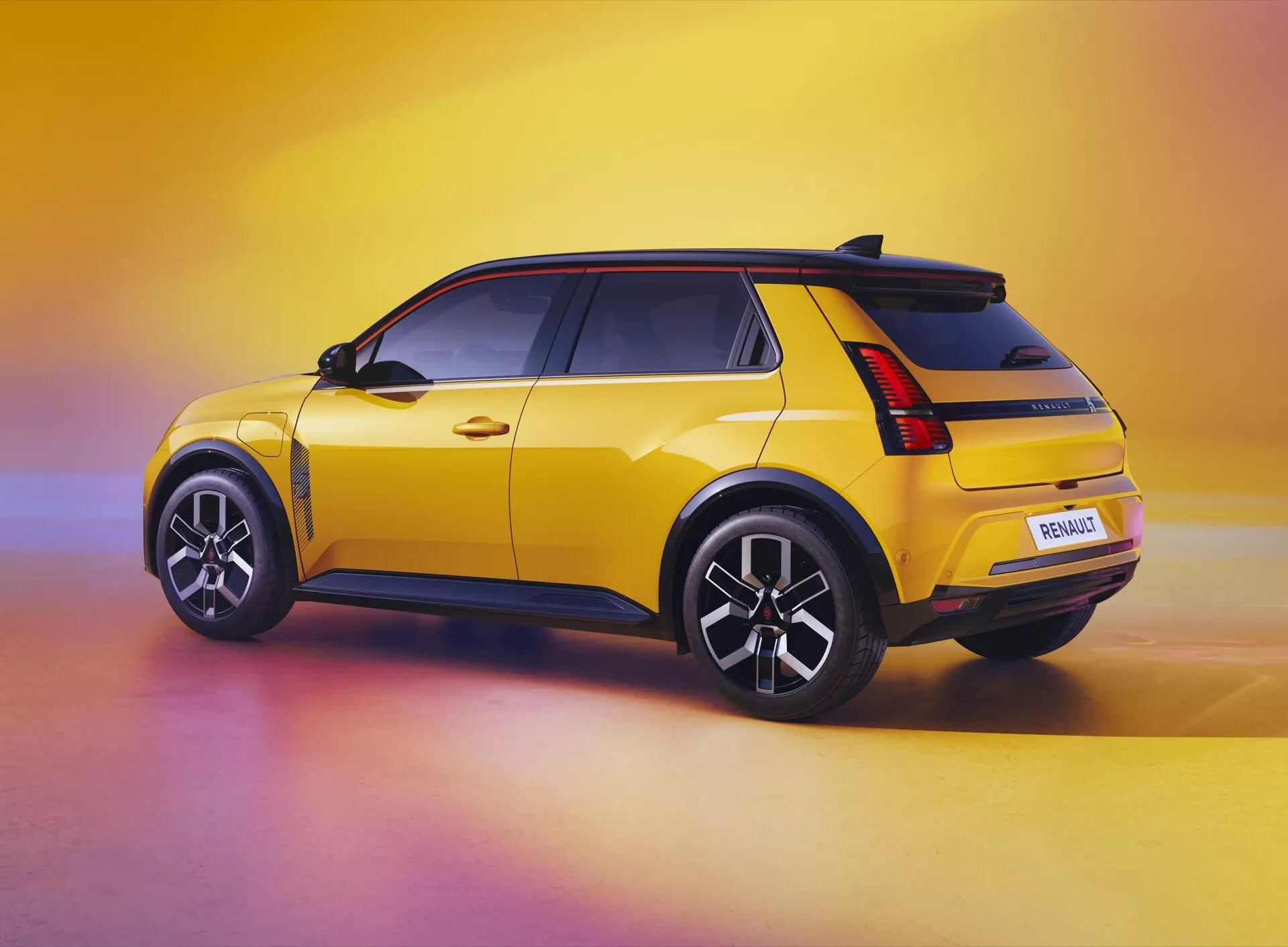 Renault R5 2024 en jaune présentant son profil latéral et son design arrière sous un angle de trois quarts, mettant en avant le becquet de toit, les feux arrière LED, les ailes musclées, les jantes à multiples branches et le pare-chocs arrière doté de technologie