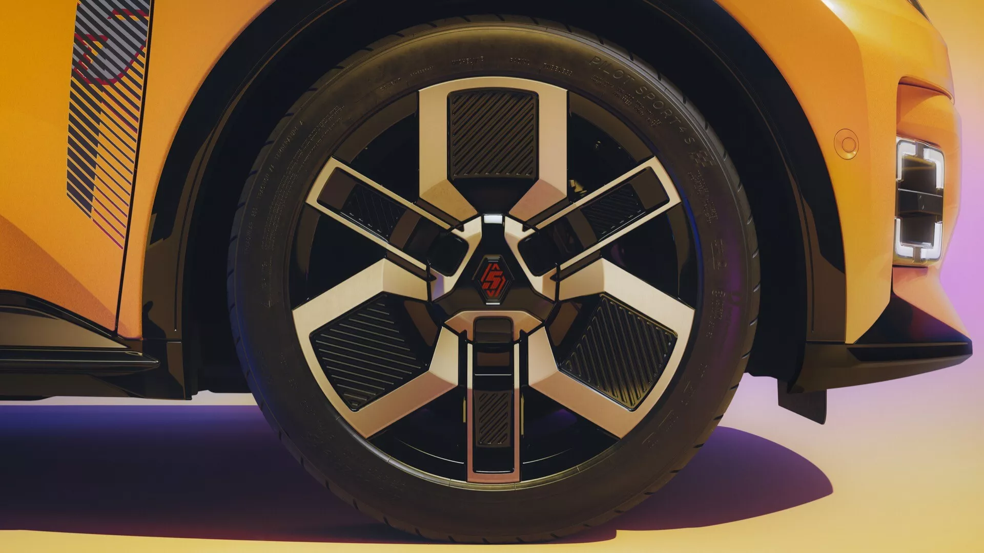 Vue rapprochée de la roue d'une Renault R5 2024, présentant un design d'alliage à multiples branches avec des finitions métalliques et noir mat et un badge central, sur fond de carrosserie orange vibrante reflétant le souci du détail dans la conception luxueuse et axée sur la performance du véhicule.