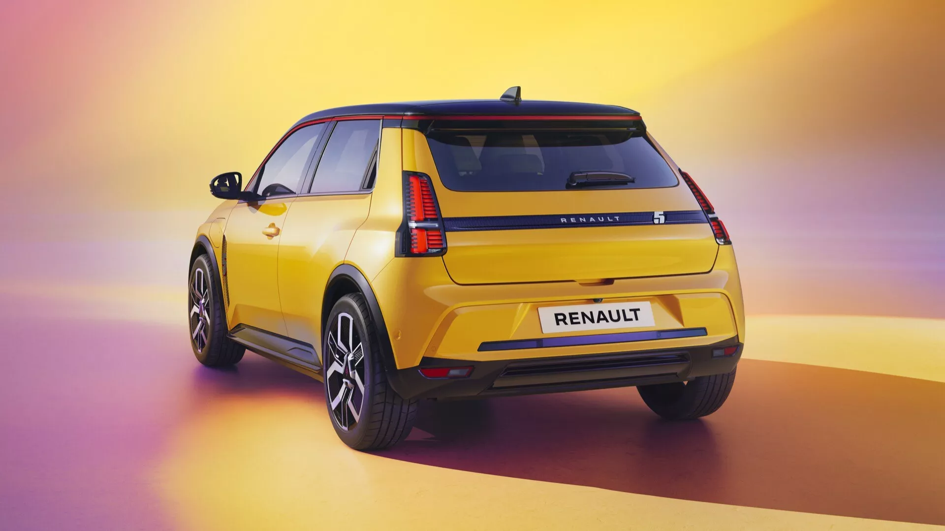 Vue arrière trois quarts d'une Renault R5 (III) 2024 jaune montrant des feux arrière LED, marque RENAULT, pare-brise arrière avec essuie-glace, roues en alliage à rayons multiples, garnitures noires, spoiler sur le toit, finition de peinture polie et antenne aileron de requin sur un fond dégradé