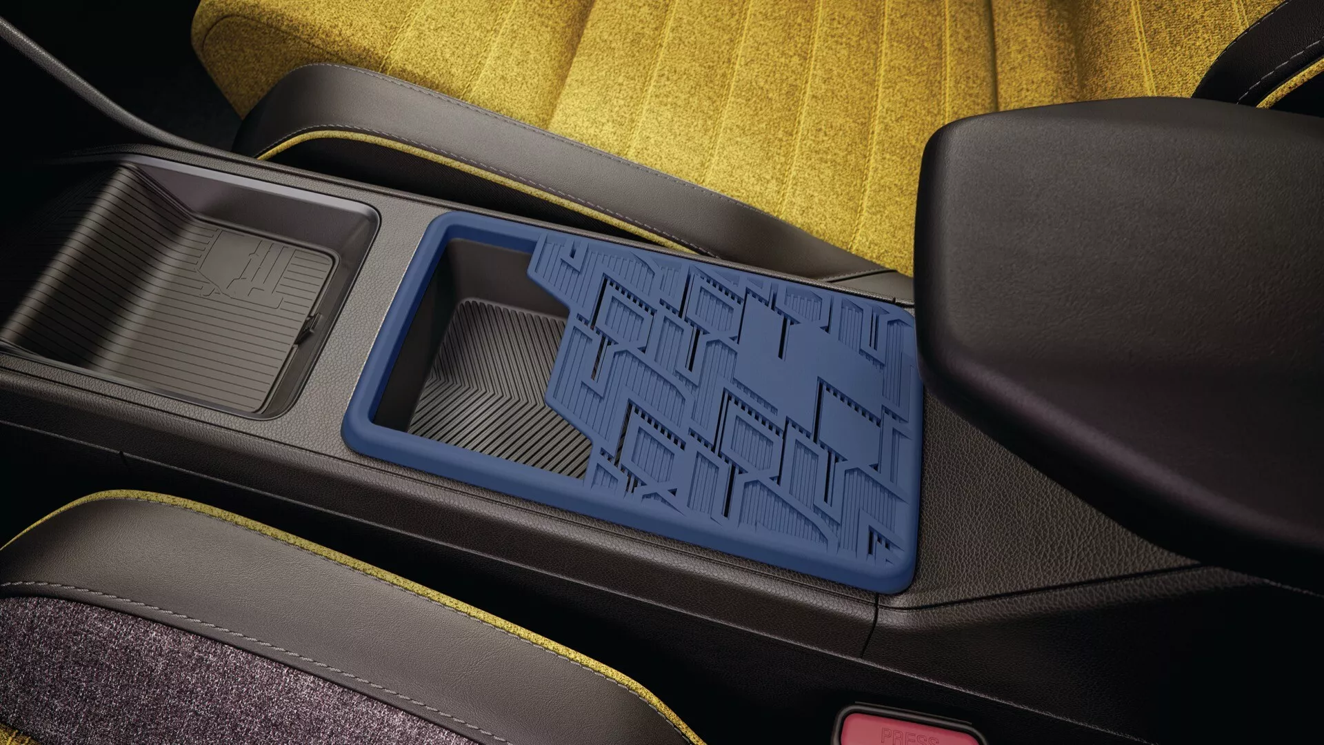 Vue de la console centrale intérieure du Renault R5 2024 avec tapis antidérapant bleu et accents de coutures jaunes montrant la conception du compartiment de rangement et les matériaux de haute qualité