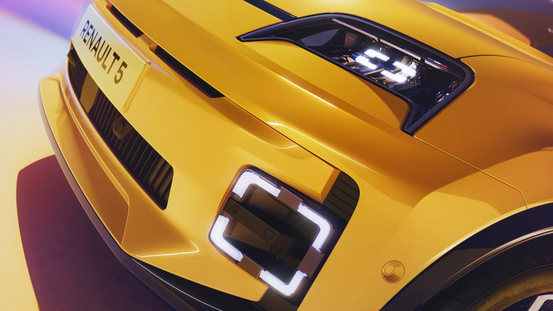 Gros plan sur le coin avant gauche du Renault R5 2024, affichant un phare LED détaillé, un design de capot sportif et une partie de la grille avec emblème illuminé en jaune vif