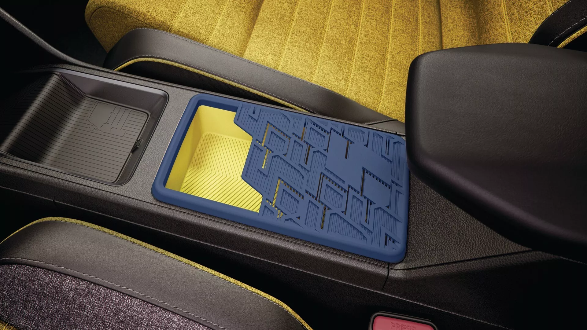 Vue rapprochée de l'intérieur du Renault R5 2024 montrant la console centrale avec un bac de rangement à motif géométrique bleu, structure noire, porte-gobelet adjacent avec insert en caoutchouc et vue partielle des sièges en tissu jaune et noir