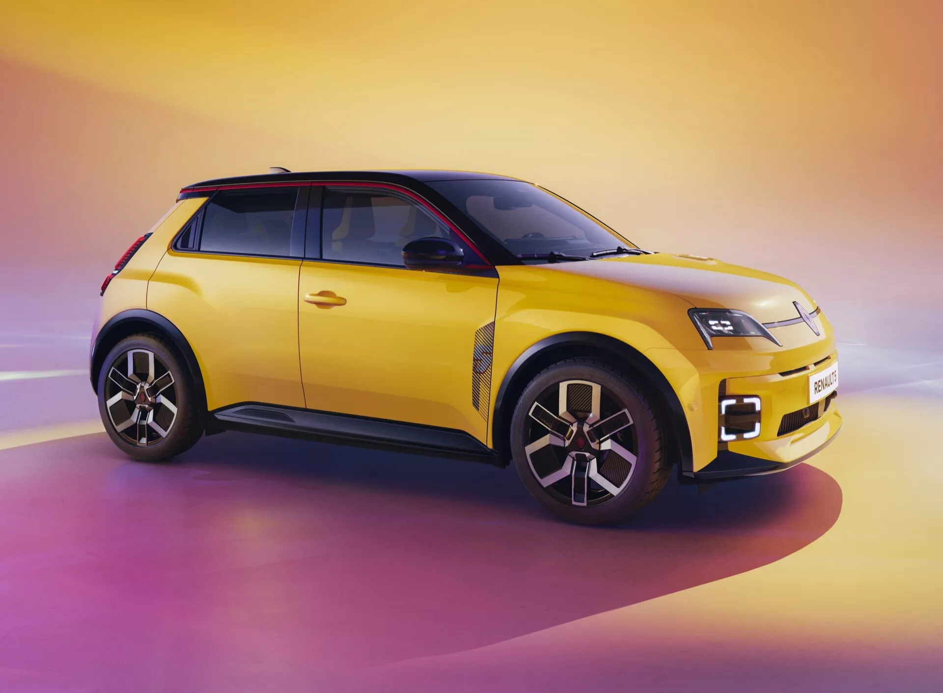Renault R5 III 2024 en jaune vibrant avec toit noir présentant son design moderne de SUV compact sous un angle avant de trois quarts, mettant en avant les phares LED, les roues en alliage à multiples branches et le schéma de couleurs bicolore sur un fond dynamique d'aube