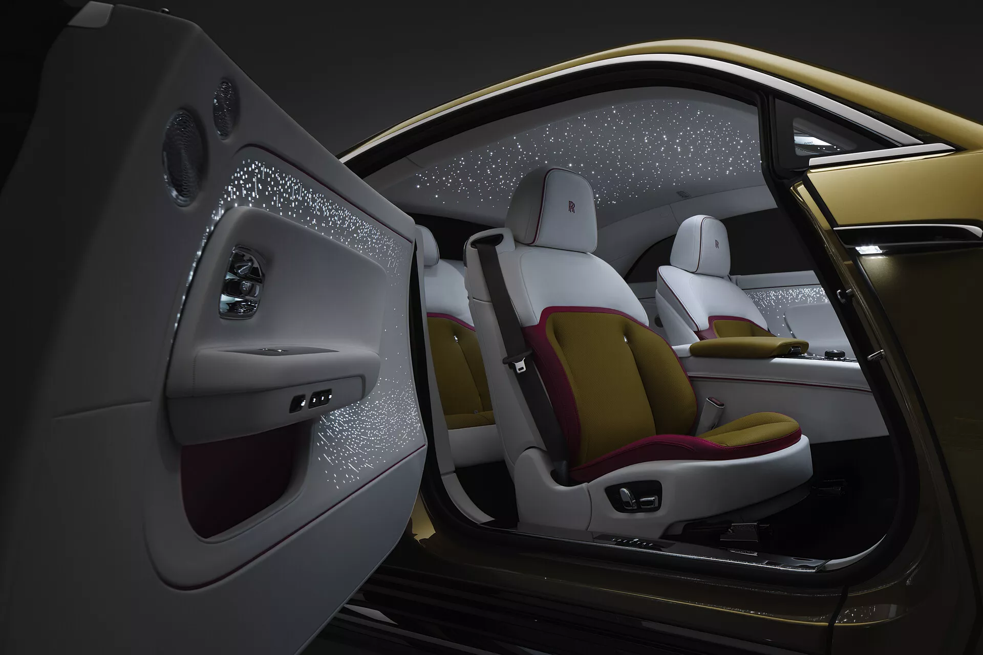 Vue intérieure rapprochée depuis la perspective du passager arrière gauche d'une Rolls-Royce Spectre 2023, mettant en avant un design luxueux avec des sièges bicolores, des caractéristiques de contrôle avancées, et un plafond étoilé.