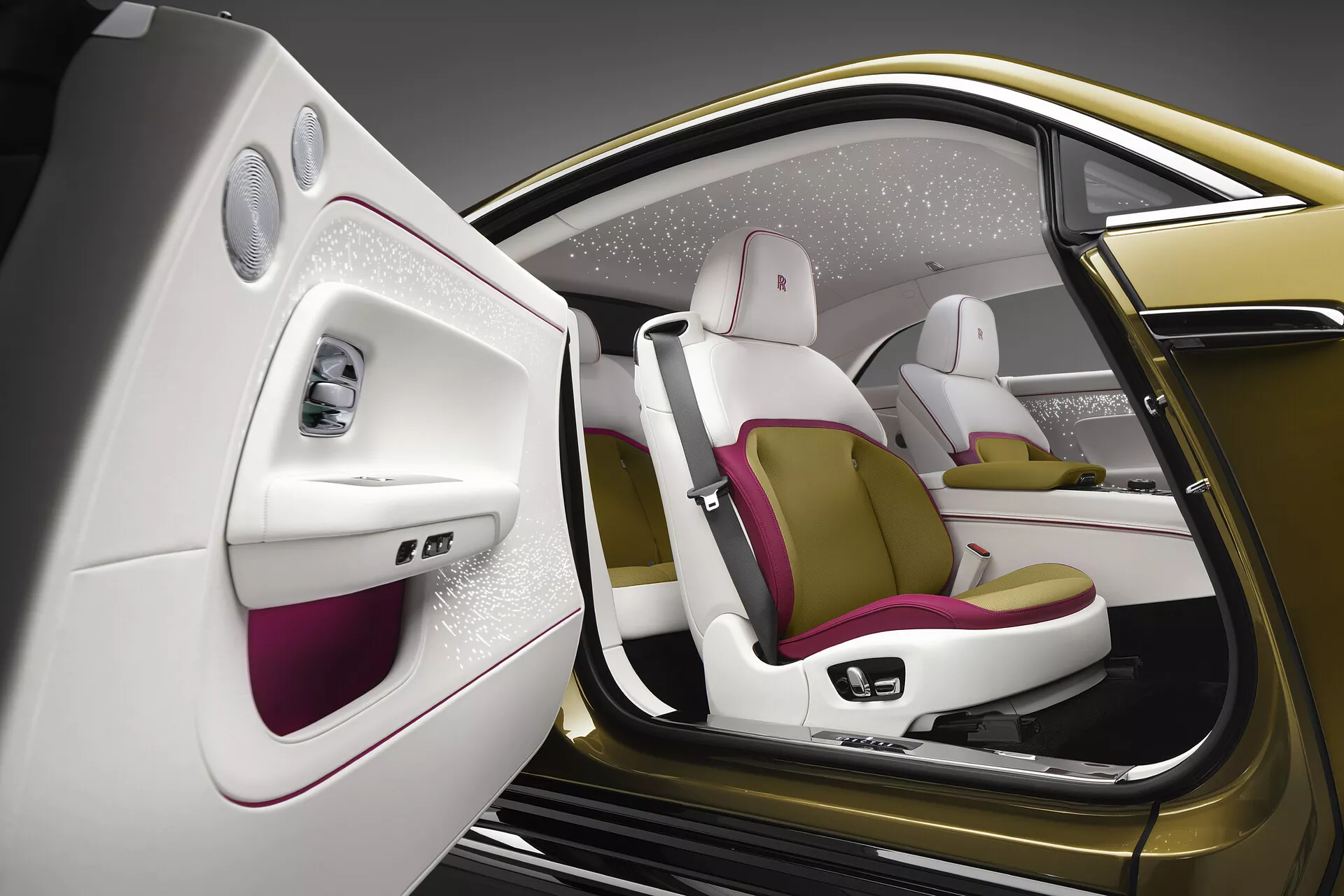 Vue intérieure détaillée du Rolls-Royce Spectre 2023, présentant son côté passager de luxe avec la porte ouverte, mettant en avant la conception minimaliste de la porte, les sièges ergonomiques bicolores avec accents magenta et matériaux haut de gamme