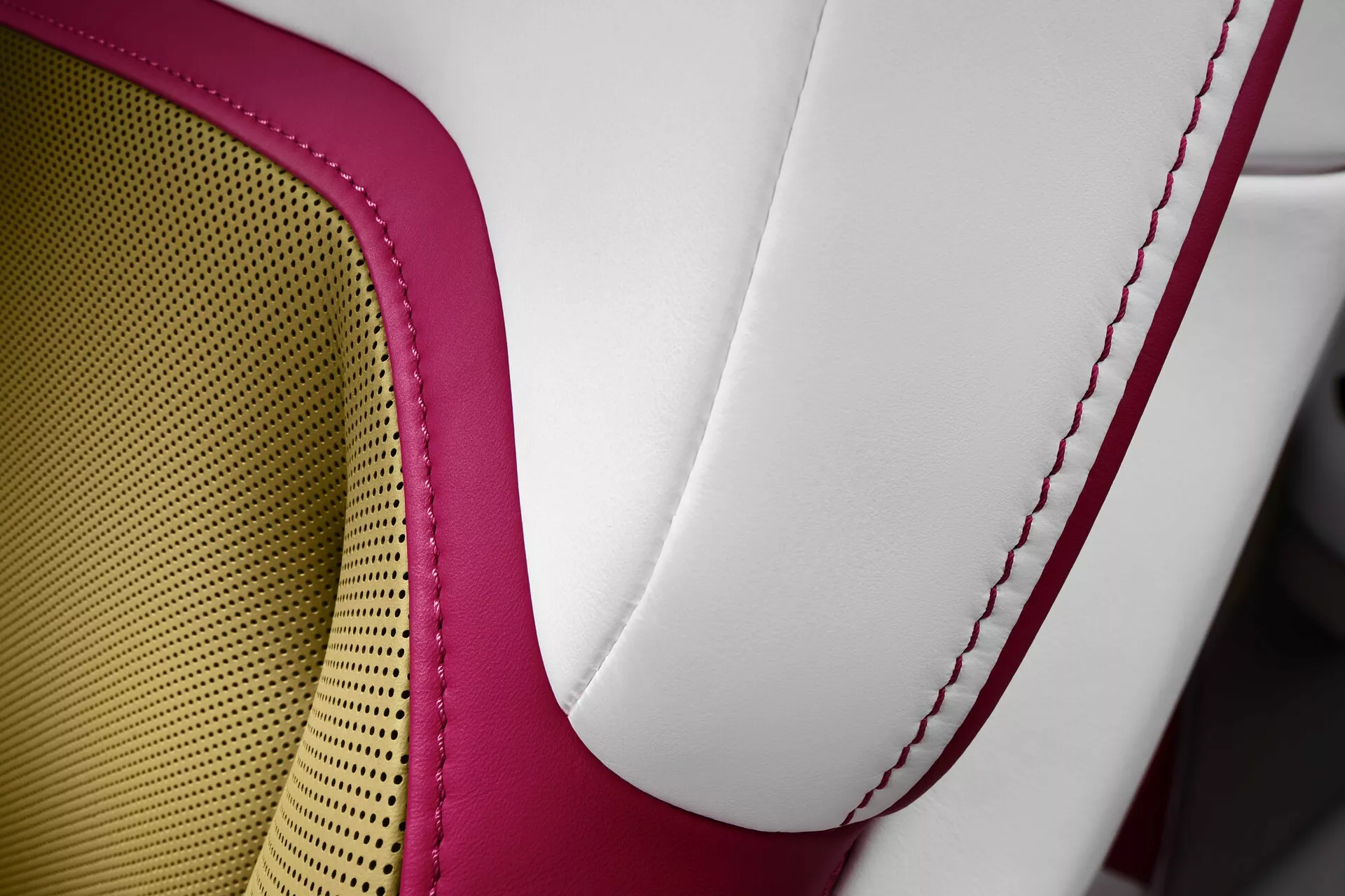 Gros plan sur le siège de Rolls-Royce Spectre 2023 présentant une sellerie en cuir bicolore de haute qualité, des coutures contrastées rouges et un motif en nid d'abeille pour la respirabilité et le confort, incarnant le luxe et l'artisanat.