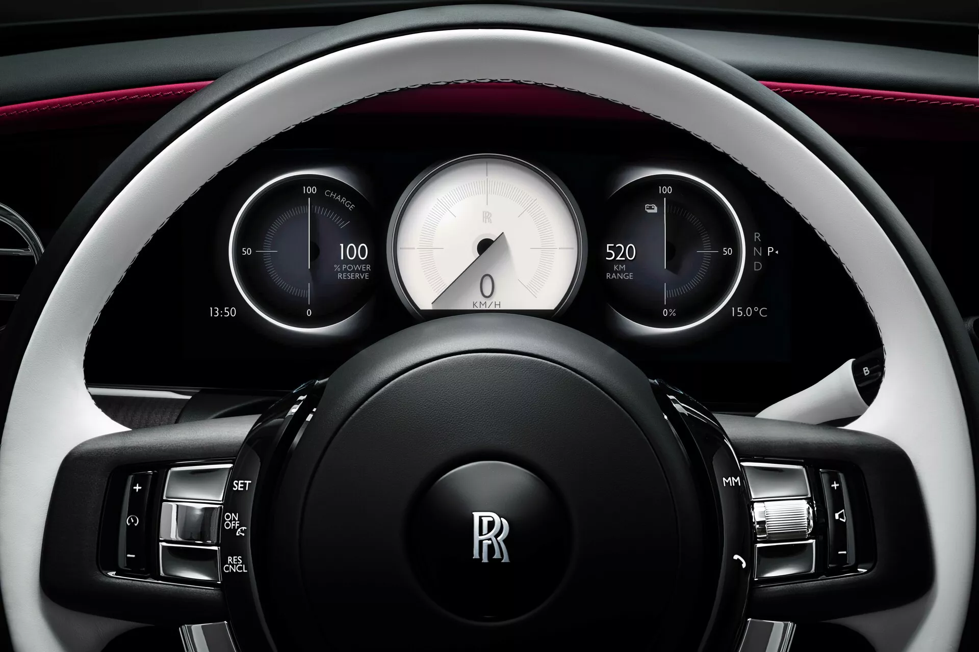 Vue rapprochée du volant et du tableau de bord de la Rolls-Royce Spectre 2023 présentant des boutons multifonctions, des jauges analogiques incluant un compteur de vitesse, une horloge et un indicateur de réserve de puissance, des écrans numériques affichant les informations de voyage et la température extérieure, le tout dans un design intérieur luxueux bicolore avec éclairage d'ambiance