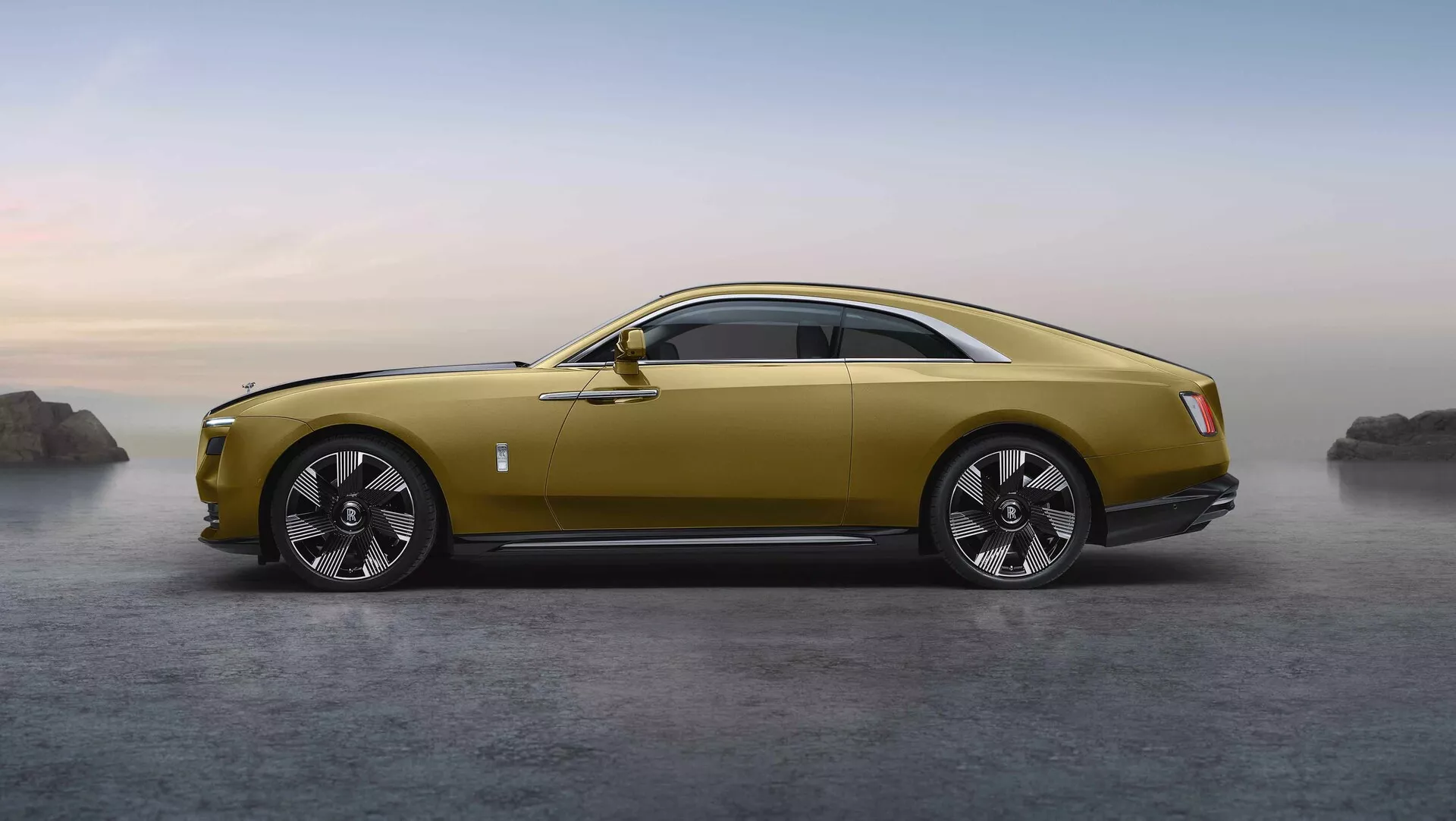 Coupé de luxe Rolls-Royce Spectre 1ère génération de 2023 en or métallique garé sur une surface brumeuse avec un paysage rocheux naturel en arrière-plan, soulignant son design élégant, son capot long, ses proportions sportives mais élégantes, et ses grandes roues en alliage multi-branches.
