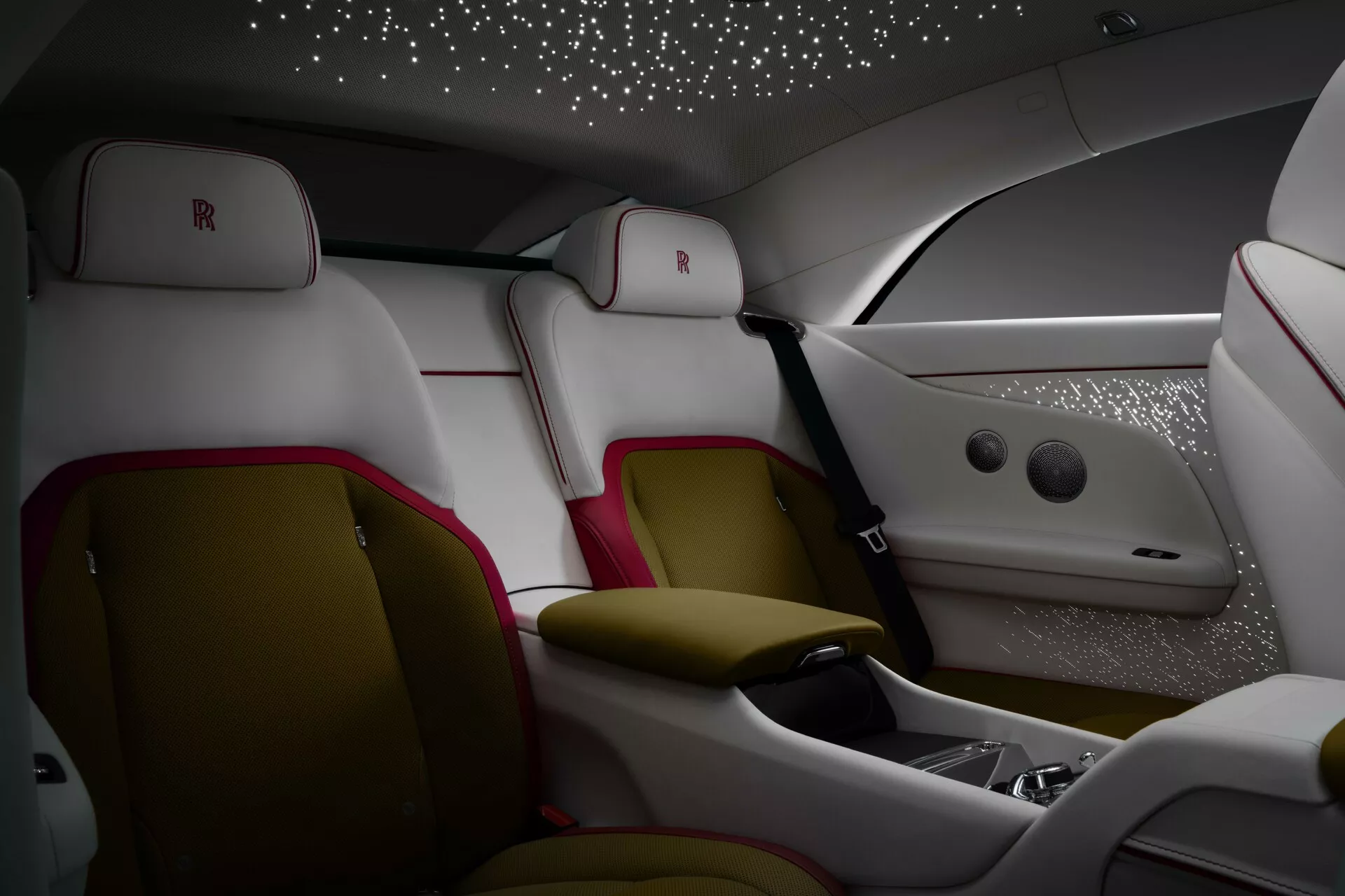 Intérieur luxueux de la Rolls-Royce Spectre première génération 2023 avec sièges arrière ergonomiques en cuir aux accents blancs et rouge foncé, console centrale avancée, tête de toit étoilée, et éclairage d'ambiance premium