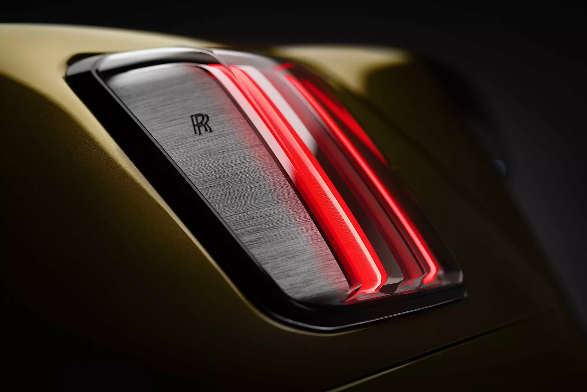 Vue rapprochée du feu arrière de la Rolls-Royce Spectre 2023 mettant en évidence la conception moderne à LED et l'emblème emblématique à double 'R' sur une carrosserie gris métallique