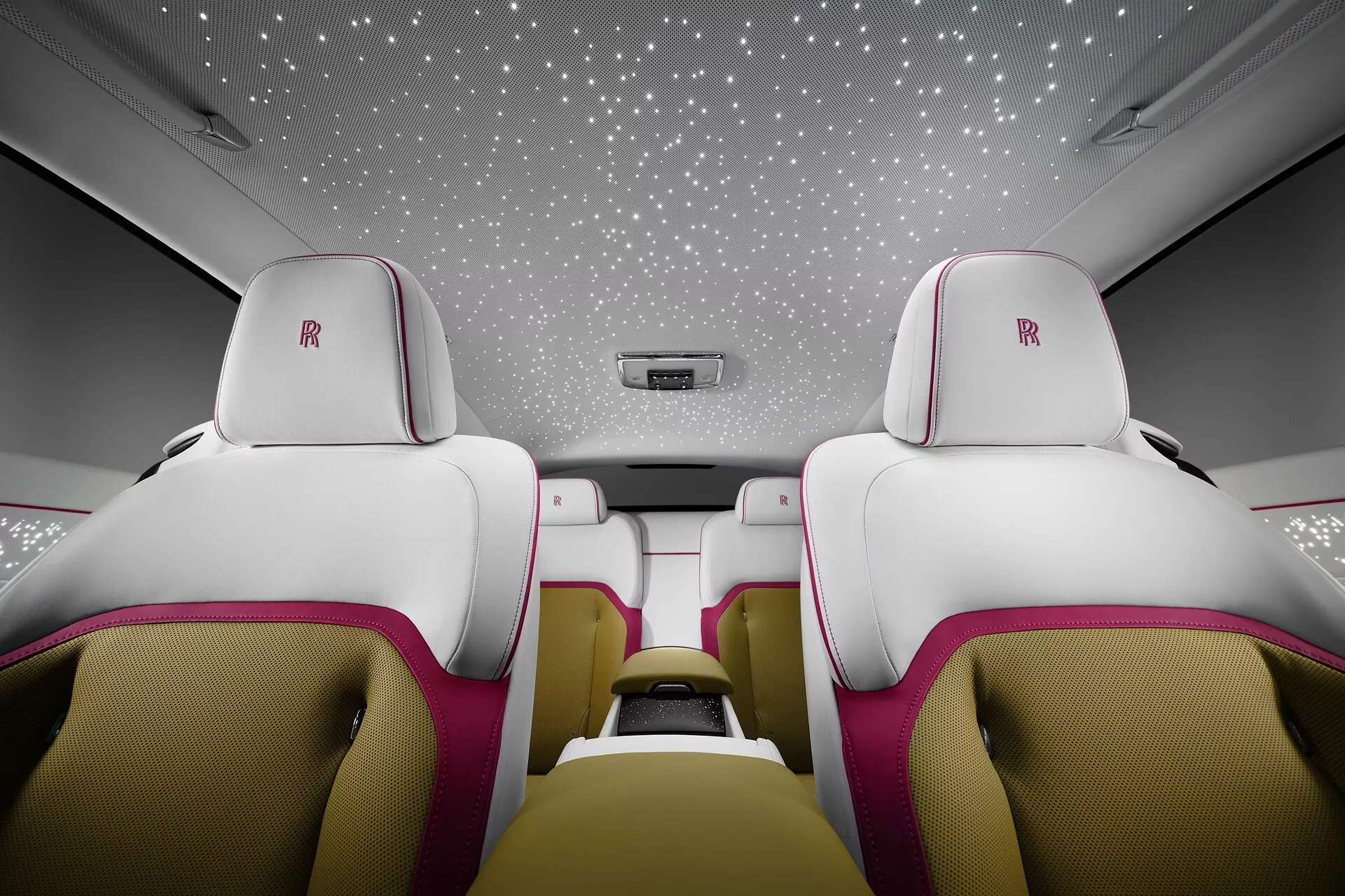 Intérieur du Rolls-Royce Spectre 2023 présentant des sièges luxueux en cuir blanc et rose, ciel étoilé et caractéristiques haut de gamme de la cabine depuis une vue orientée vers l'arrière
