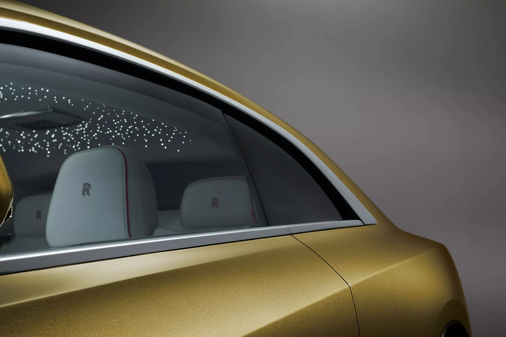 Vue de côté détaillée de la Rolls-Royce Spectre 2023, présentant la finition métallique dorée, le design de la fenêtre arrière, la technologie des portes élégantes, et les détails de marque de luxe