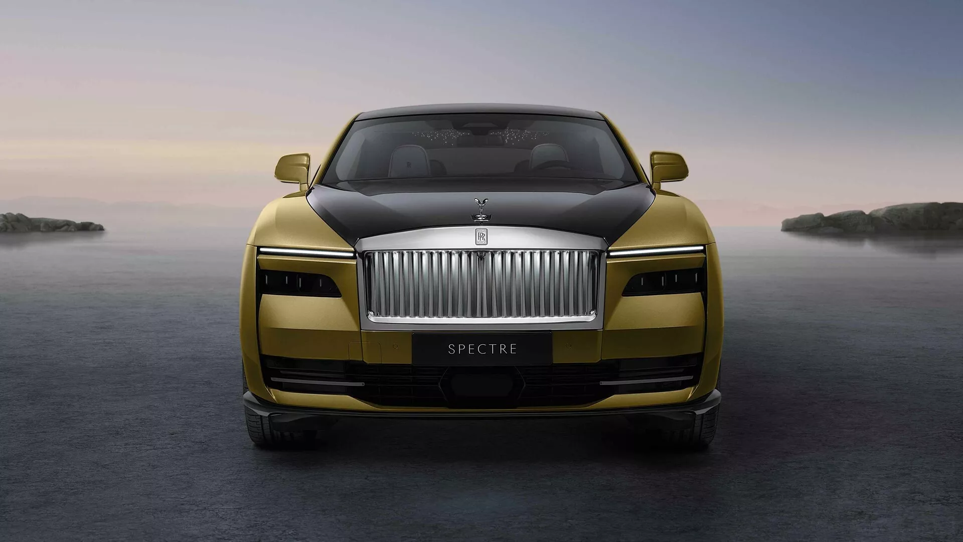 Vue de face de la Rolls-Royce Spectre 2023 présentant une grille proéminente, un emblème, des phares LED et une finition métallique avec des caractéristiques avancées mises en évidence sur un fond serein