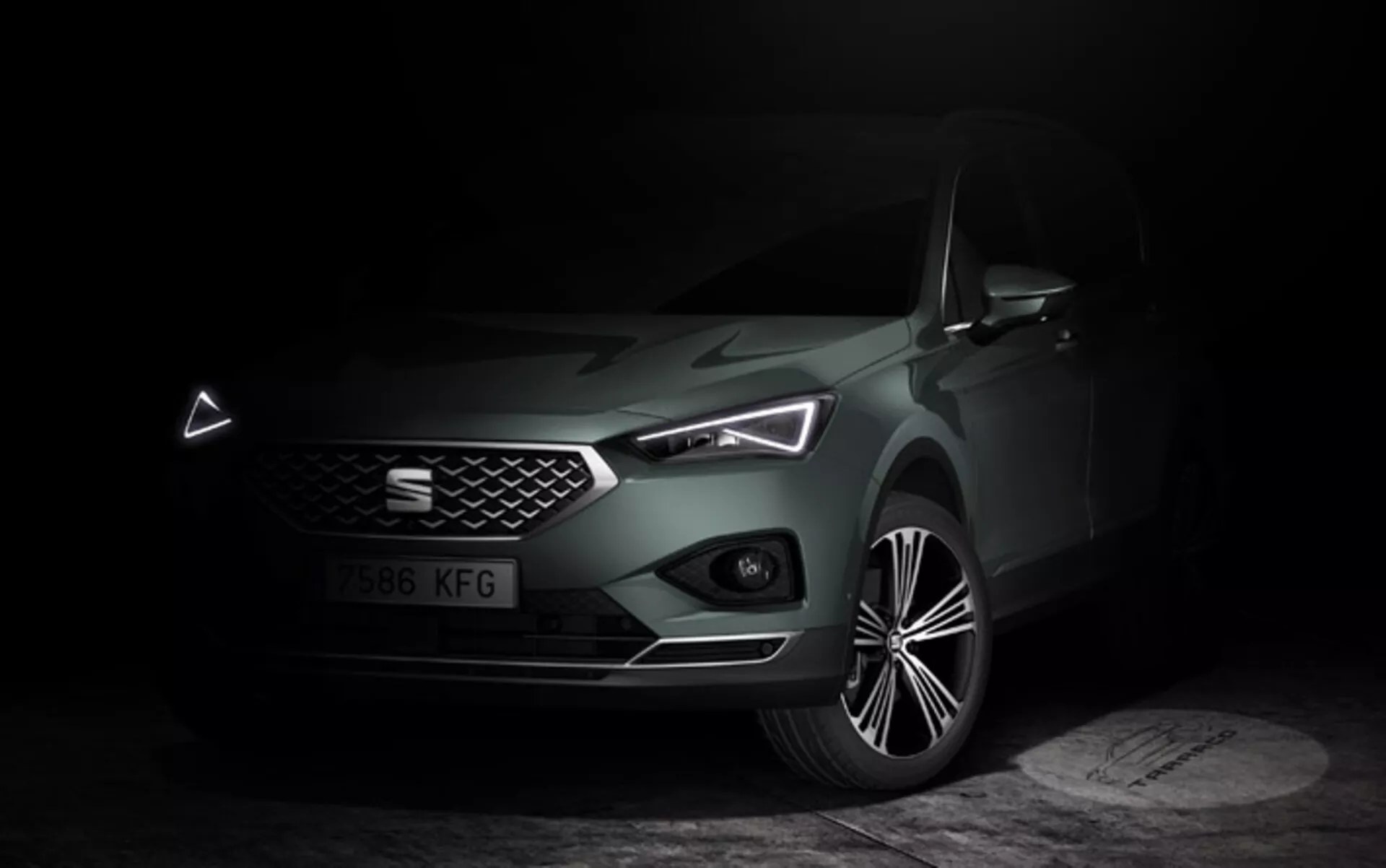 Seat Tarraco 2019 photographiée en éclairage tamisé, mettant en avant ses caractéristiques de design moderne depuis un angle avant latéral, soulignant les phares LED, la grille proéminente avec badge, le pare-chocs avant avec prises d'air visibles et le design de roue en alliage à multiples rayons.