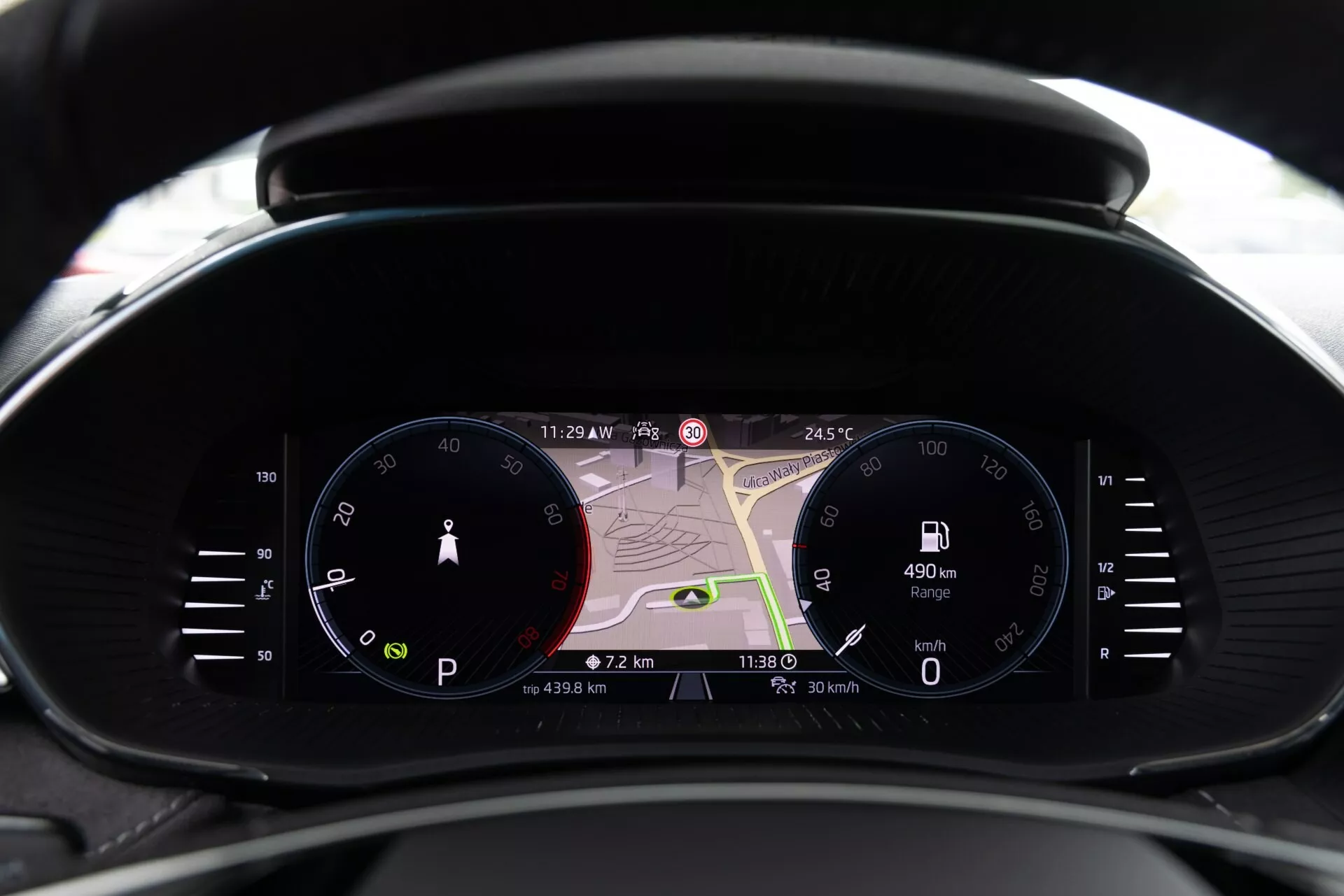 Vue en gros plan du tableau de bord moderne de la Skoda Fabia 2021 depuis la perspective du conducteur, avec un compteur de vitesse analogique, un grand écran numérique avec carte de navigation et un compte-tours numérique. Les écrans affichent 23h29, 24,5°C, une autonomie de 490 km, une vitesse actuelle de 0 km/h et des données de voyage. Combine un design traditionnel et contemporain avec une technologie avancée, incluant la navigation en temps réel, les informations du conducteur et les indicateurs de connectivité.
