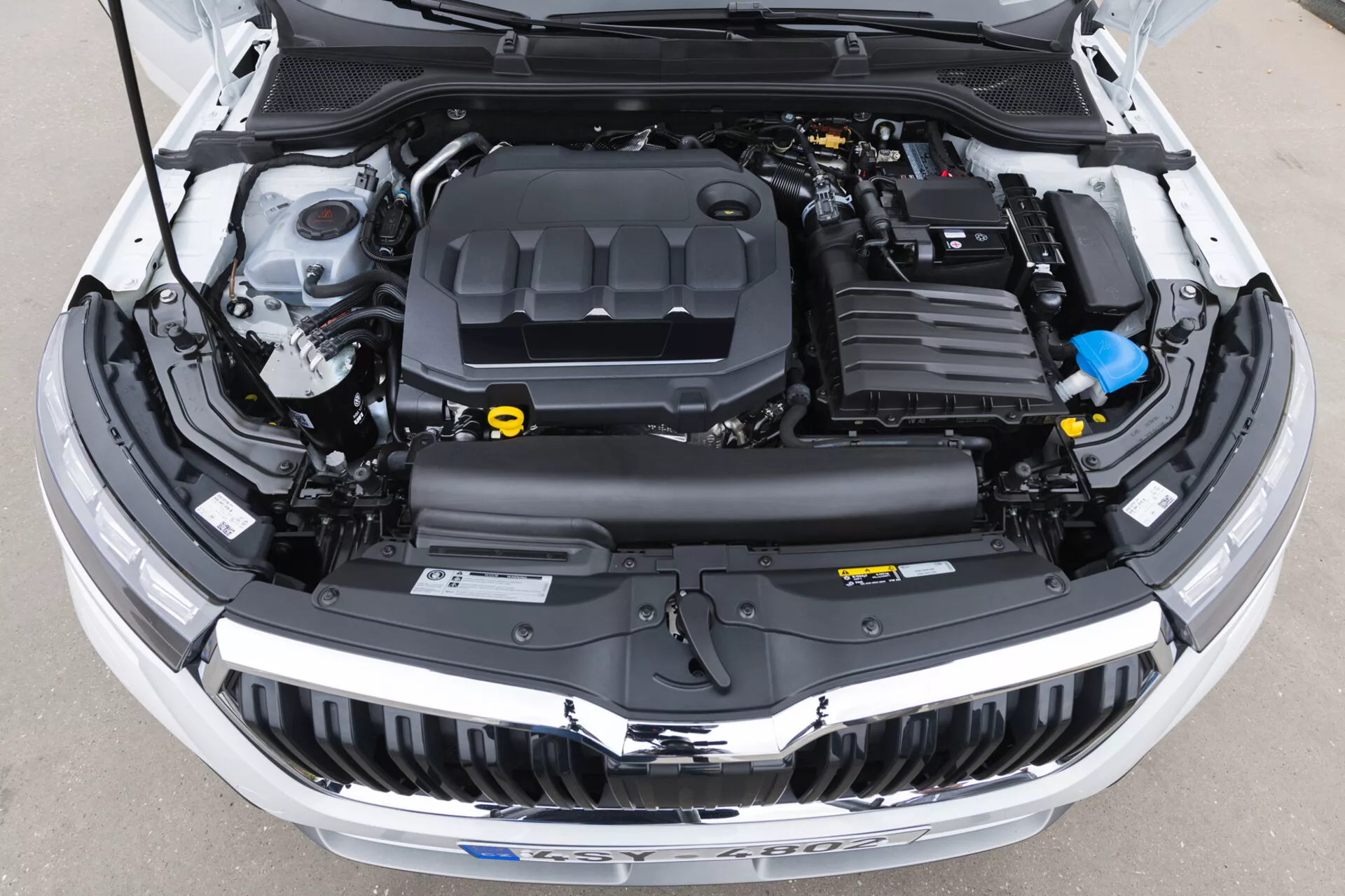 Vue en plongée du compartiment moteur de la Skoda Kamiq 2019 avec le capot ouvert montrant le couvercle du moteur, le système d'admission d'air, la batterie, le réservoir de liquide de refroidissement et divers autres composants clairement visibles, idéal pour l'éducation à la technologie automobile et l'entretien des véhicules
