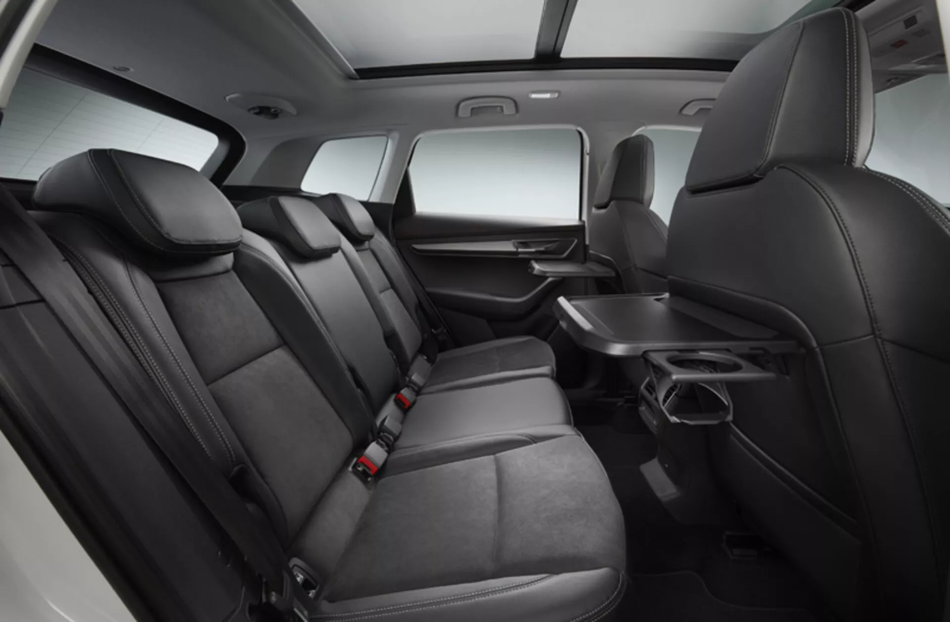 Intérieur du Skoda Karoq 2017 montrant une zone de sièges arrière spacieuse et confortable avec une sellerie premium bicolore, contrôle du climat arrière, accoudoir rabattable avec porte-gobelets et système de divertissement