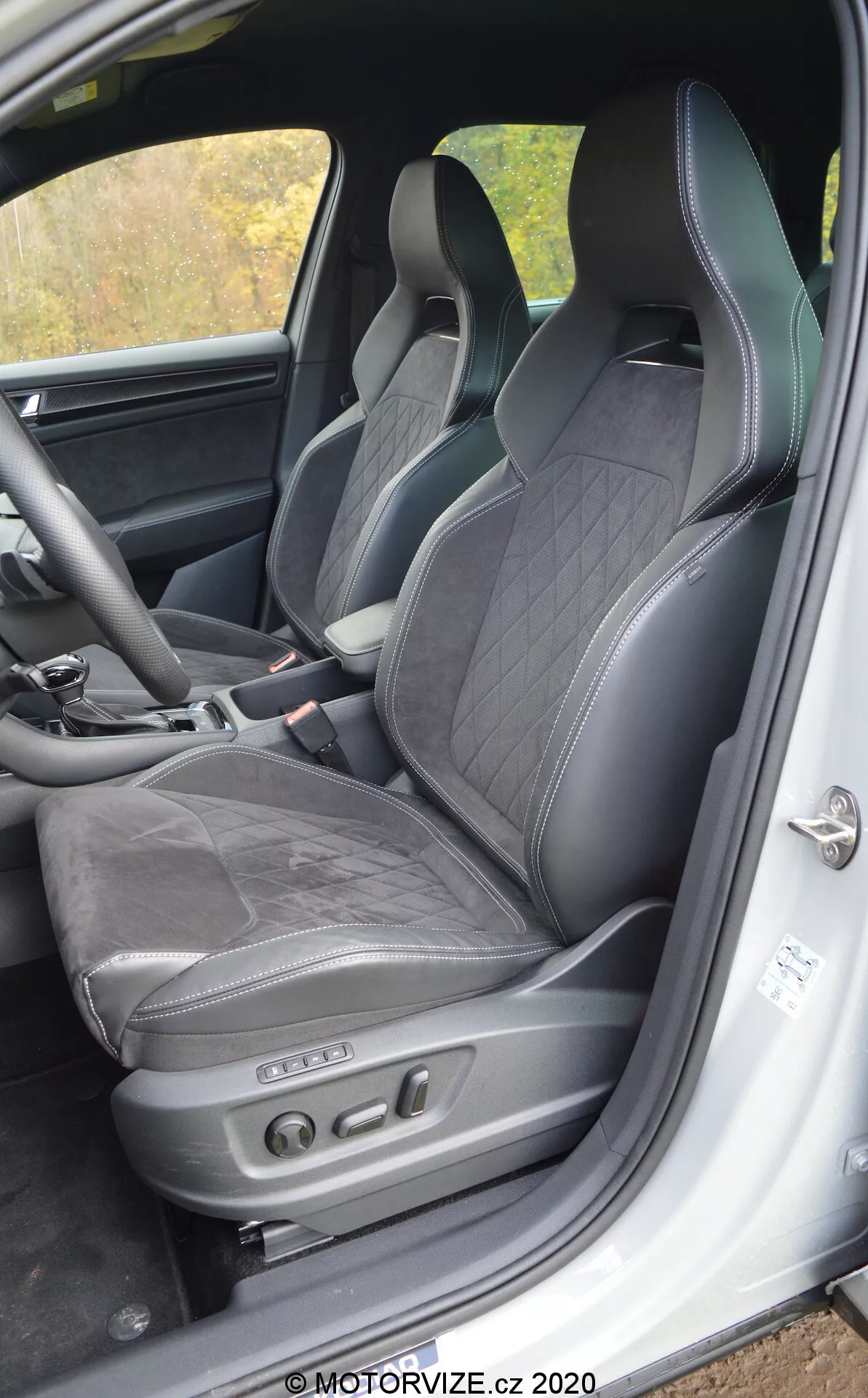 Vue intérieure d'une Skoda Kodiaq 2017 centrée sur le siège du conducteur et son environnement, avec une sellerie en cuir noir à coutures en losange, un appui-tête intégré, un soutien latéral pour une conduite dynamique et des réglages électroniques du siège avec boutons de contrôle. Les éléments visibles incluent le cadre inférieur de la porte avec plaque de seuil et une unité de haut-parleur, indicatifs d'un intérieur luxueux et sportif avec une technologie de siège avancée.