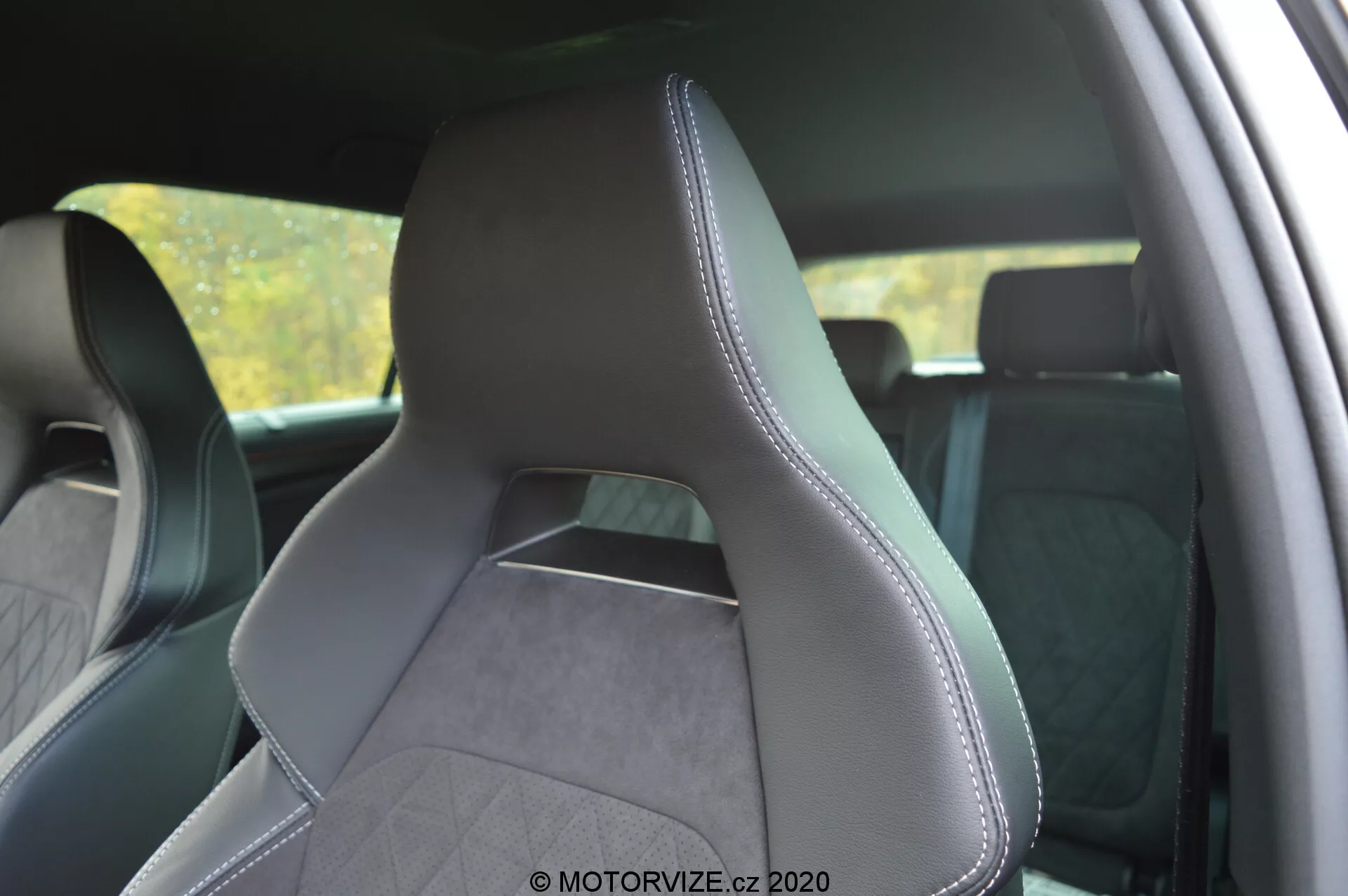 Intérieur d'une Škoda Kodiaq 2017 axé sur le siège conducteur avant d'une perspective latérale arrière, mettant en évidence le revêtement en cuir et en tissu texturé avec des coutures précises le long des bords. Le siège au design moderne et sportif comporte des renforts latéraux prononcés pour un soutien accru, un appui-tête intégré et un motif en losanges suggérant une esthétique premium. L'arrière-plan de l'intérieur est légèrement flou pour mettre en valeur le siège.