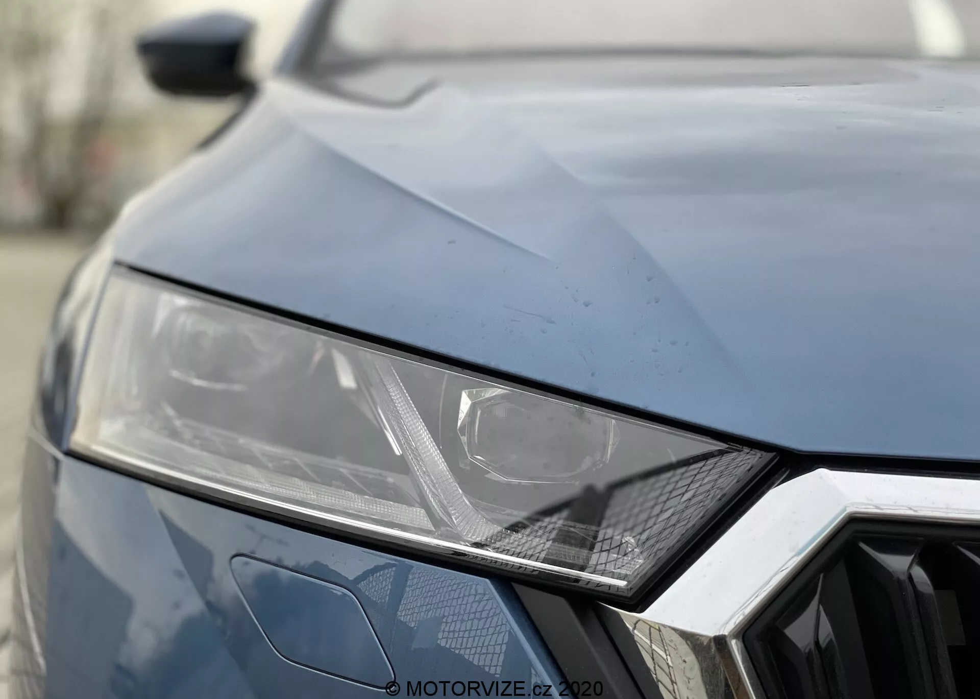 Vue rapprochée de l’avant de la Skoda Octavia 2020. Couleur sombre, affichant le phare gauche avec un design angulaire élégant suggérant une technologie LED ou HID, motif hexagonal géométrique de la calandre et plis angulaires sur le capot pour un look sportif.