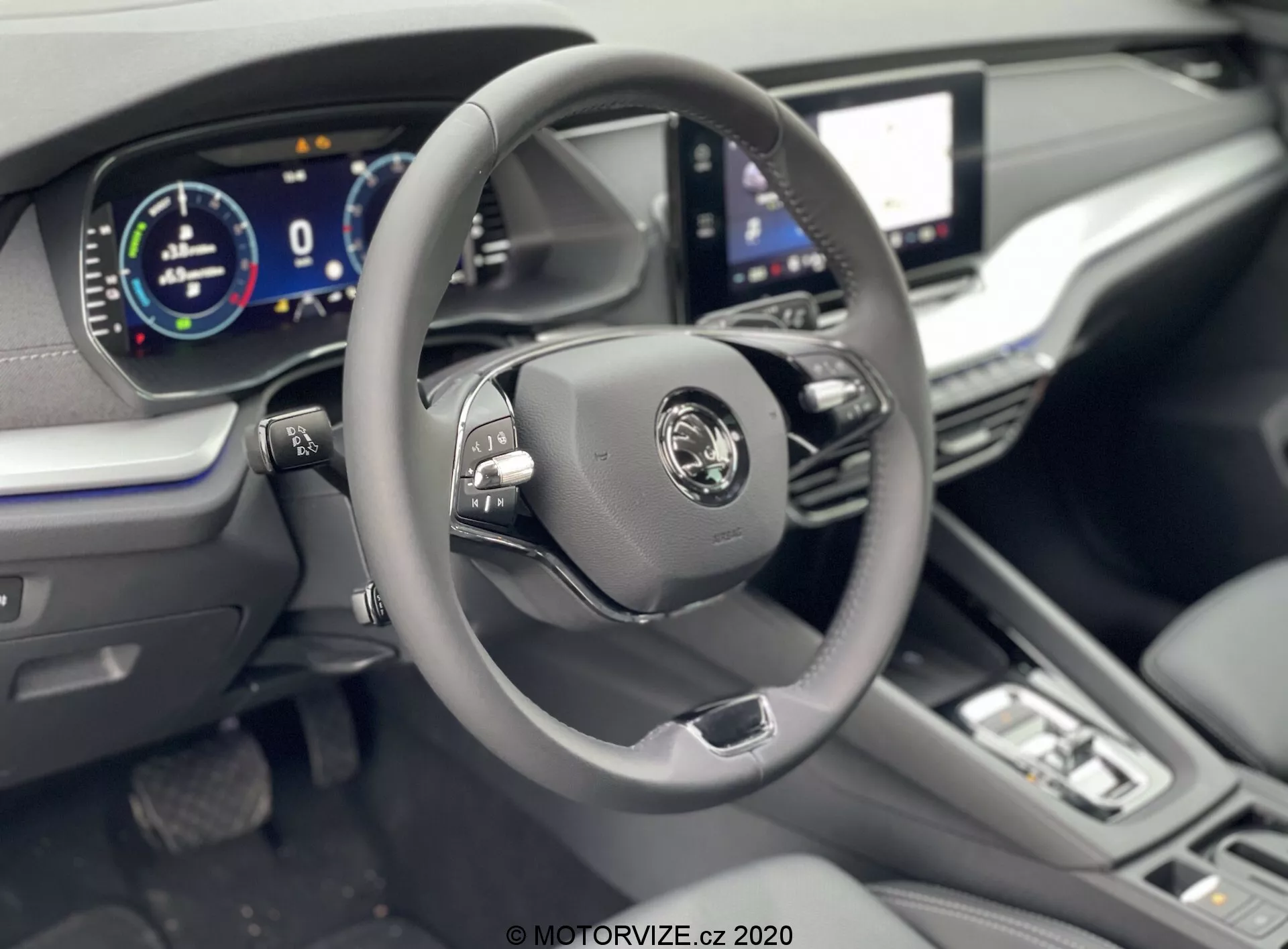 Intérieur de la Skoda Octavia Limousine 2020 se concentrant sur la zone du conducteur depuis un angle légèrement surélevé, montrant un volant moderne à trois branches avec boutons multifonctions, logo central du fabricant et tableau de bord entièrement numérique affichant 0 km/h. Les caractéristiques visibles incluent un grand écran tactile d'infodivertissement, des boutons et cadrans de contrôle du climat minimalistes, un levier de vitesse indiquant une transmission automatique, ainsi qu'un volant en cuir, une sellerie en cuir et des accents chromés pour une sensation de luxe