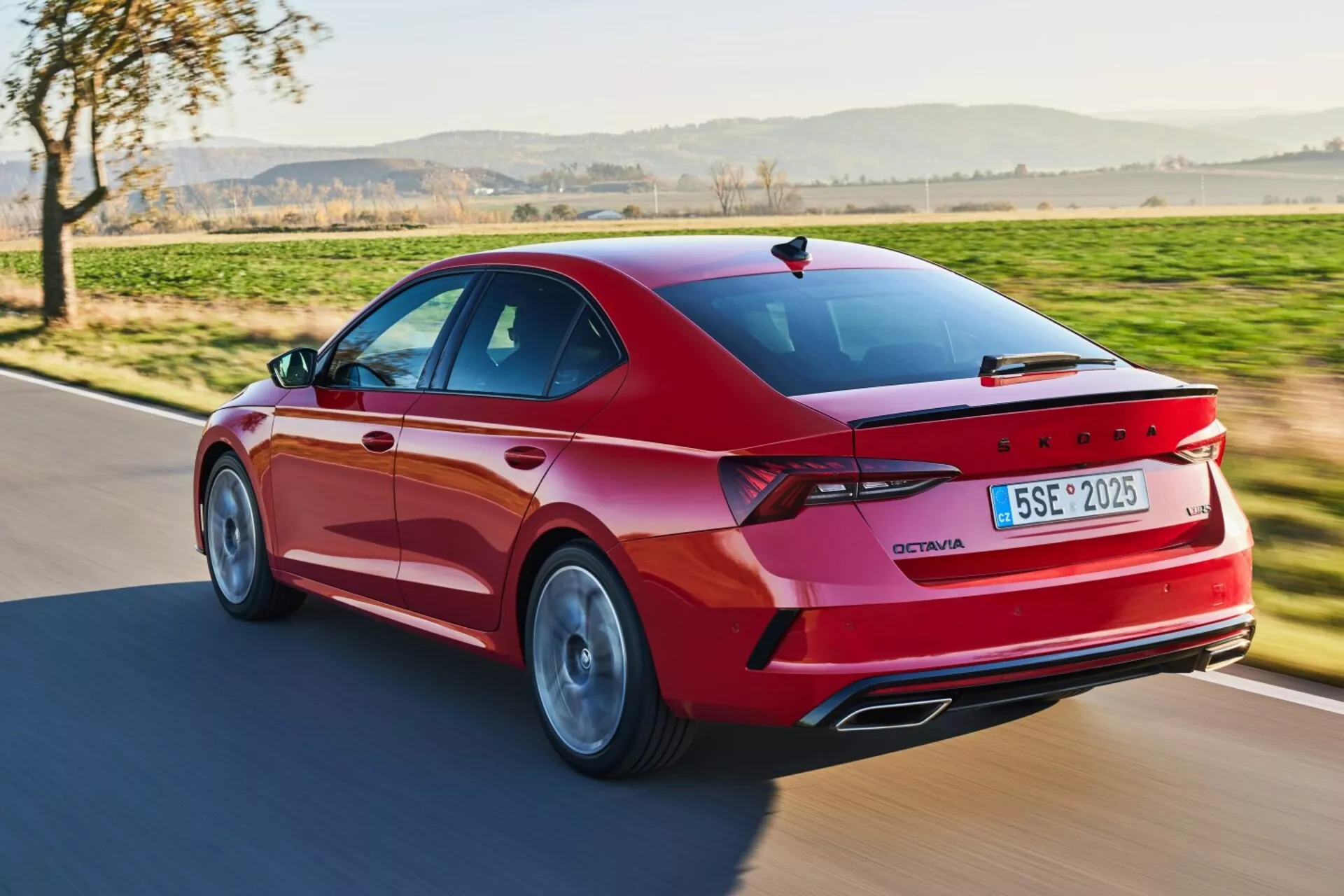 Vue arrière dynamique trois quarts d'une limousine Skoda Octavia de 2017 en rouge, mettant en avant son extérieur sportif avec des feux arrière LED, des jantes en alliage et des caractéristiques avancées sous la lumière naturelle du jour