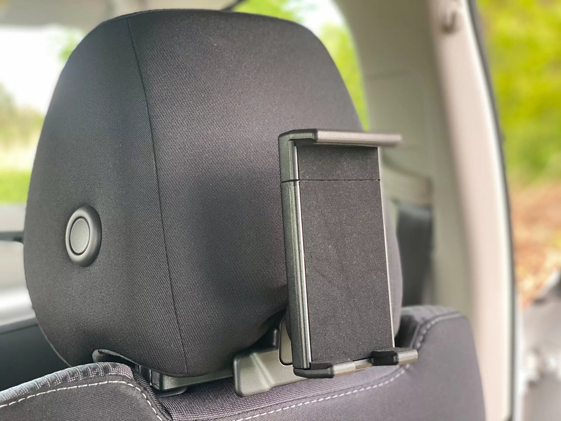 Vue rapprochée de l'appuie-tête dans une Škoda Octavia 2020 (Octavia-Limousine) depuis un angle intérieur latéral, mettant en évidence le mécanisme de réglage de l'appuie-tête et l'accessoire pour accrocher les manteaux. L'appuie-tête présente une finition en tissu ou en cuir avec un motif subtil, axé sur le confort et le design.