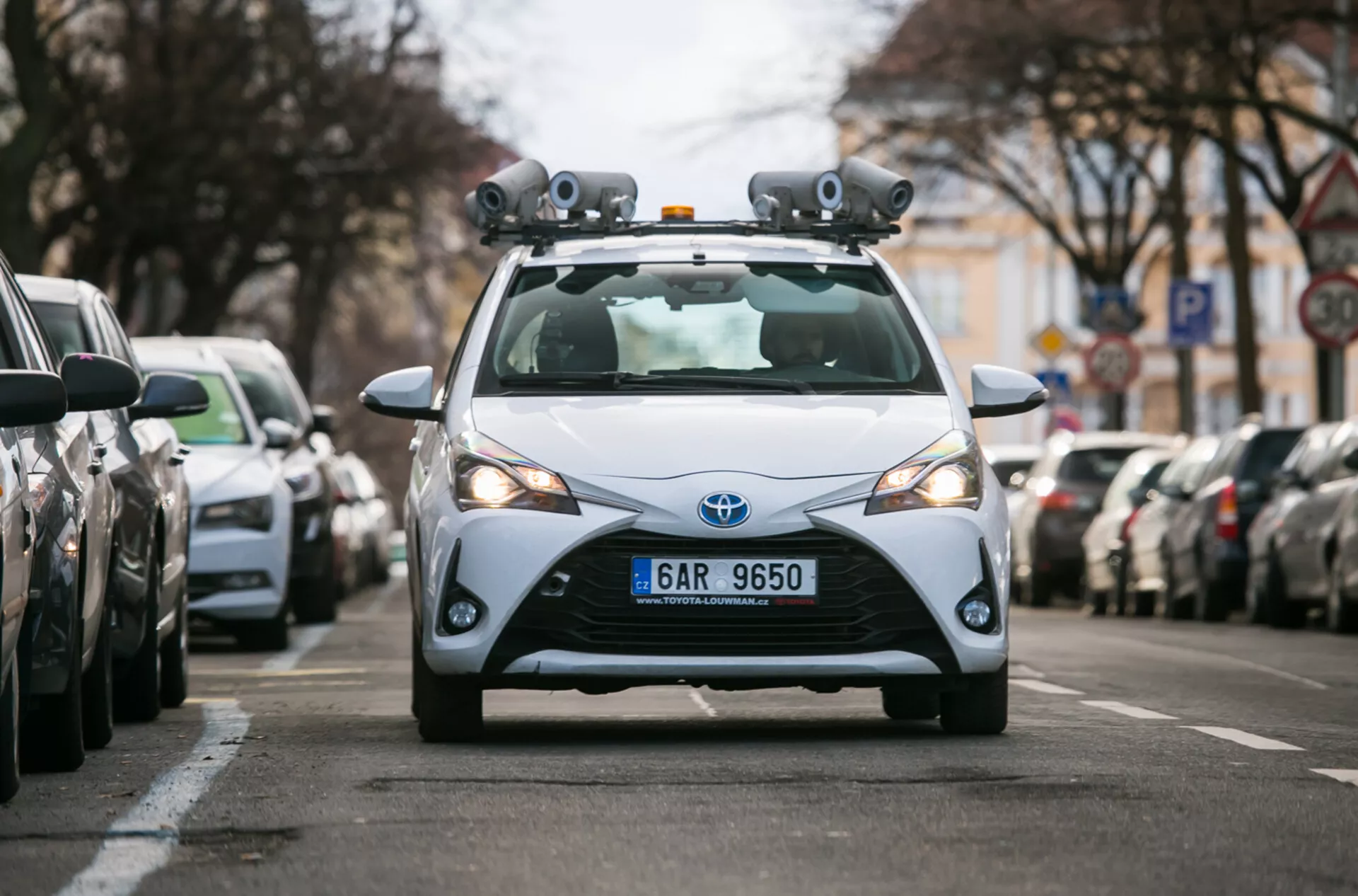 Hatchback Toyota 2017 équipé de capteurs LiDAR et de caméras pour la technologie de conduite autonome, capturé d'une perspective frontale sur une rue urbaine
