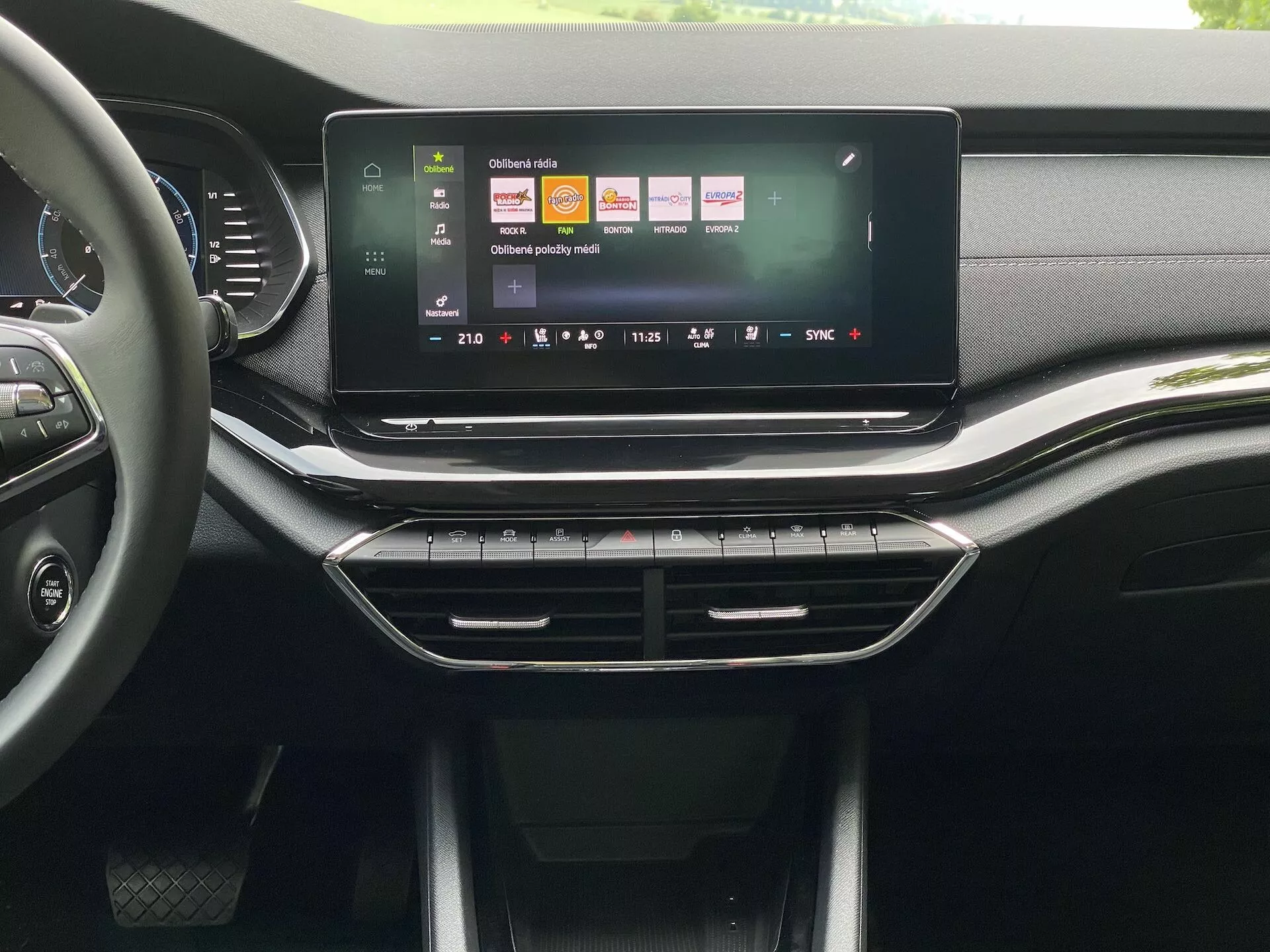 Intérieur de la Škoda Octavia 2020 limousine, mettant en avant la console centrale et le système d'infodivertissement vu depuis un siège avant. Le grand écran tactile orienté en paysage affiche une interface utilisateur dynamique avec des icônes pour la navigation, la lecture multimédia et les réglages du véhicule. Sous l'écran tactile, des aérateurs d'air épurés avec une garniture chromée, suivis de boutons physiques et de cadrans pour le système de climatisation. Le tableau de bord et la console présentent un mélange de texture similicuir et de plastiques mats et brillants, suggérant un design de haute qualité pour un marché de milieu à haut de gamme.