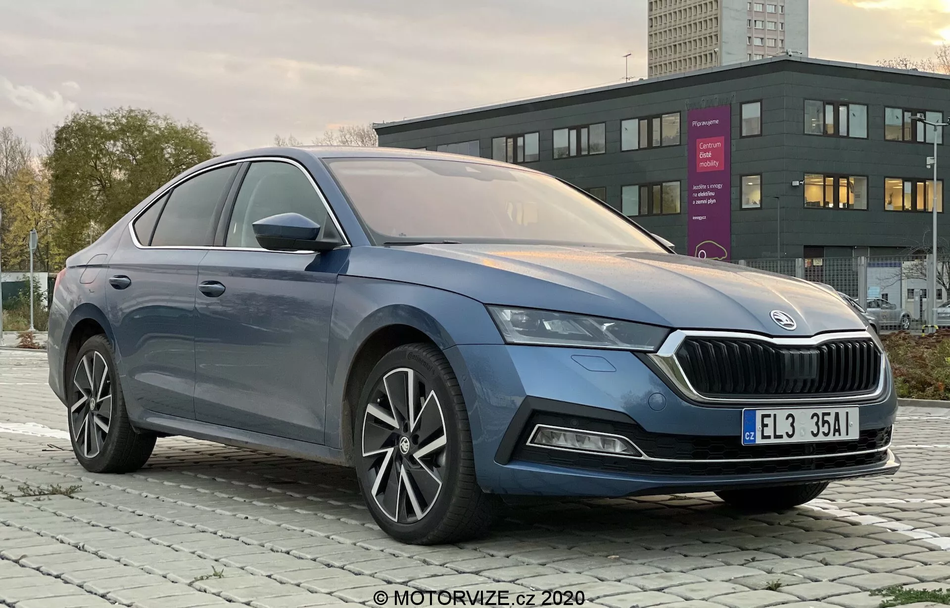 Photo professionnelle de la Skoda Octavia Limousine 2020 à quatre portes prise sous un angle trois quarts avant-gauche, montrant clairement la calandre distinctive, les phares LED élégants, le pare-chocs avant avec d'éventuels feux antibrouillard, des lignes de carrosserie fluides, des jantes en alliage à rayons multiples, des rétroviseurs intégrant les clignotants et une finition des vitres en chrome premium dans un environnement urbain ou suburbain à l'aube ou au crépuscule.