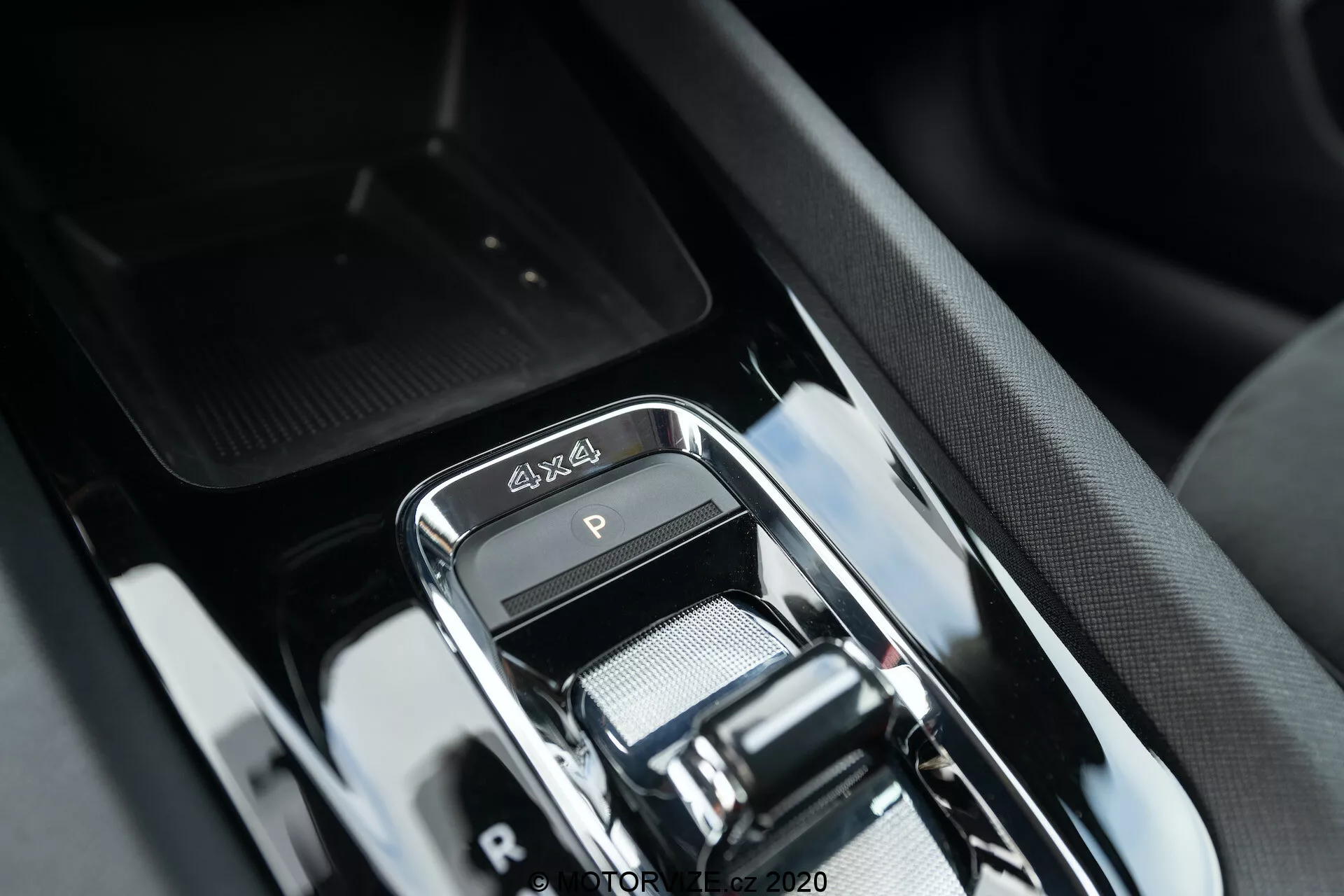 Gros plan sur le levier de vitesses du luxueux intérieur de la Skoda Octavia Scout 2020, avec un sélecteur de vitesses électronique moderne finition chromée, un emblème 4x4, une finition noire brillante élégante et un design sophistiqué de la console centrale avec des boutons environnants et un compartiment de rangement suggéré.