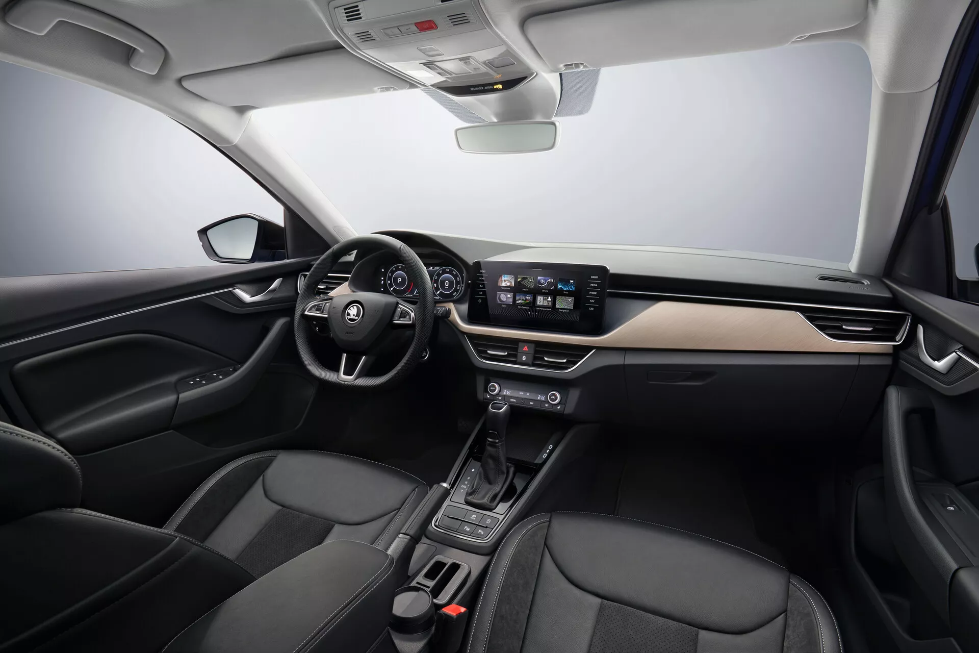 Vue intérieure de la Skoda Scala 2019 montrant les zones du conducteur et du passager, comprenant un volant à gauche avec commandes intégrées, tableau de bord moderne avec accents en métal brossé, cluster d'instruments numérique derrière le volant, système d'infodivertissement avec écran tactile de 8 pouces, console centrale minimaliste avec sélecteur de vitesse automatique, sièges en cuir noir accentué et technologie avancée du véhicule incluant le contrôle automatique du climat et les fonctionnalités de connectivité, sous un éclairage de studio doux soulignant la disposition spacieuse et le design ergonomique de la voiture.