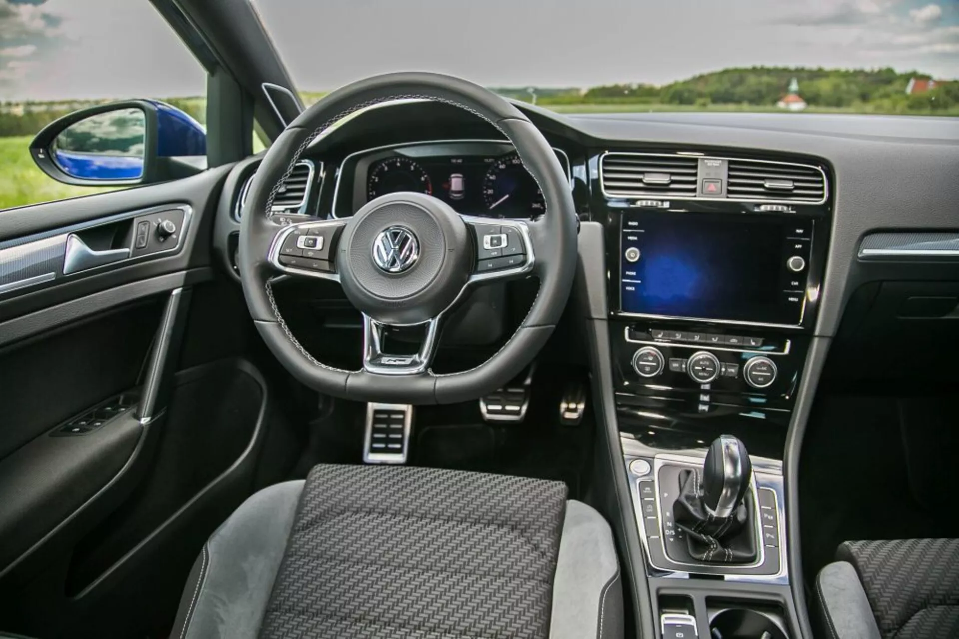 Vue intérieure d'une Skoda Scala 2019 du point de vue du passager avant mettant en vedette un volant multifonctions avec le logo Volkswagen, un tableau de bord numérique, un écran tactile sur la console centrale et une commande automatique de la climatisation
