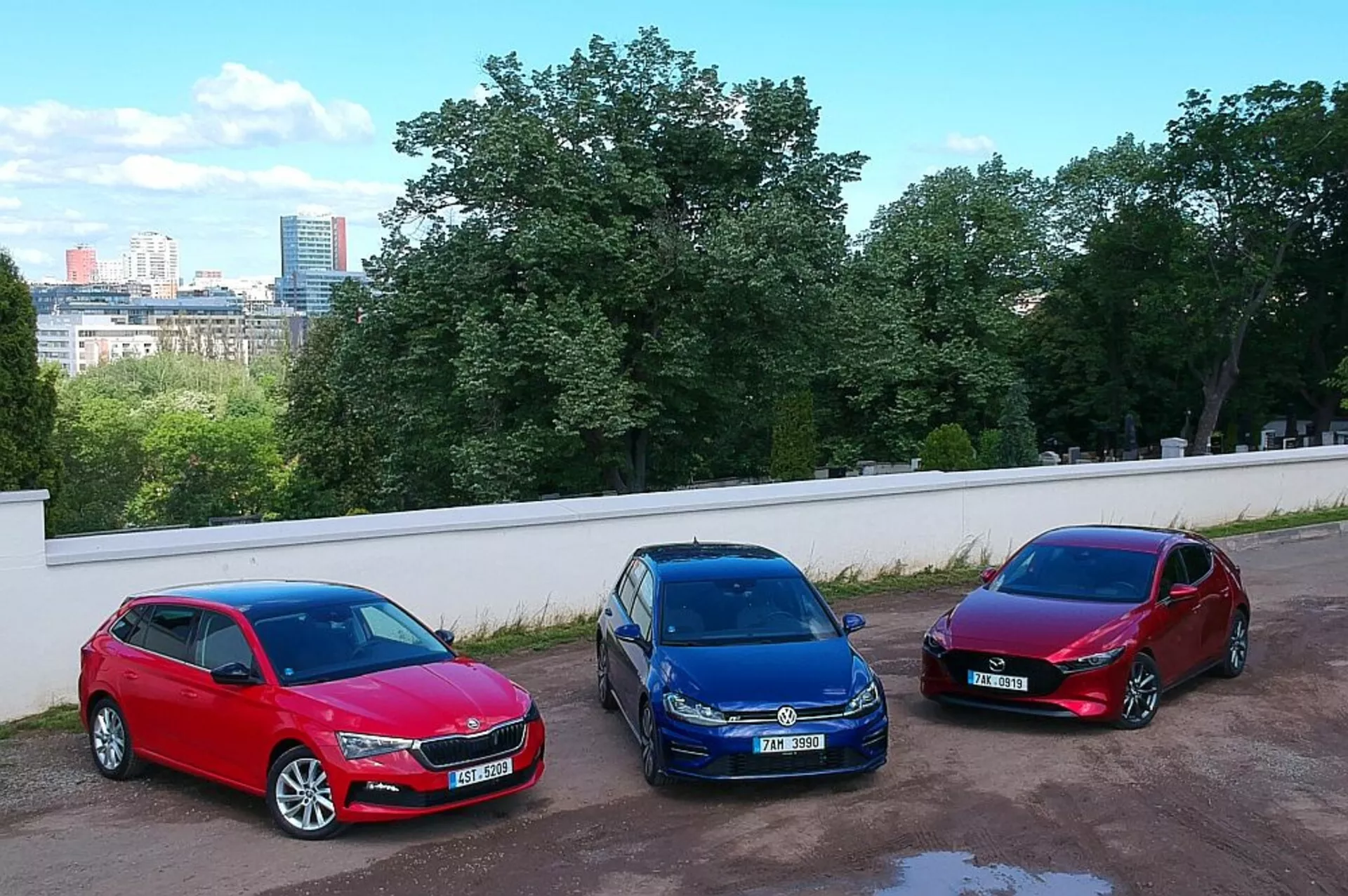 Hatchbacks Skoda Scala de 2019 garées côte à côte dans un cadre urbain, présentant les couleurs rouge, bleu et bourgogne avec une prise de vue en plongée depuis une position surélevée, mettant en évidence leurs roues en alliage, phares halogènes et designs aérodynamiques