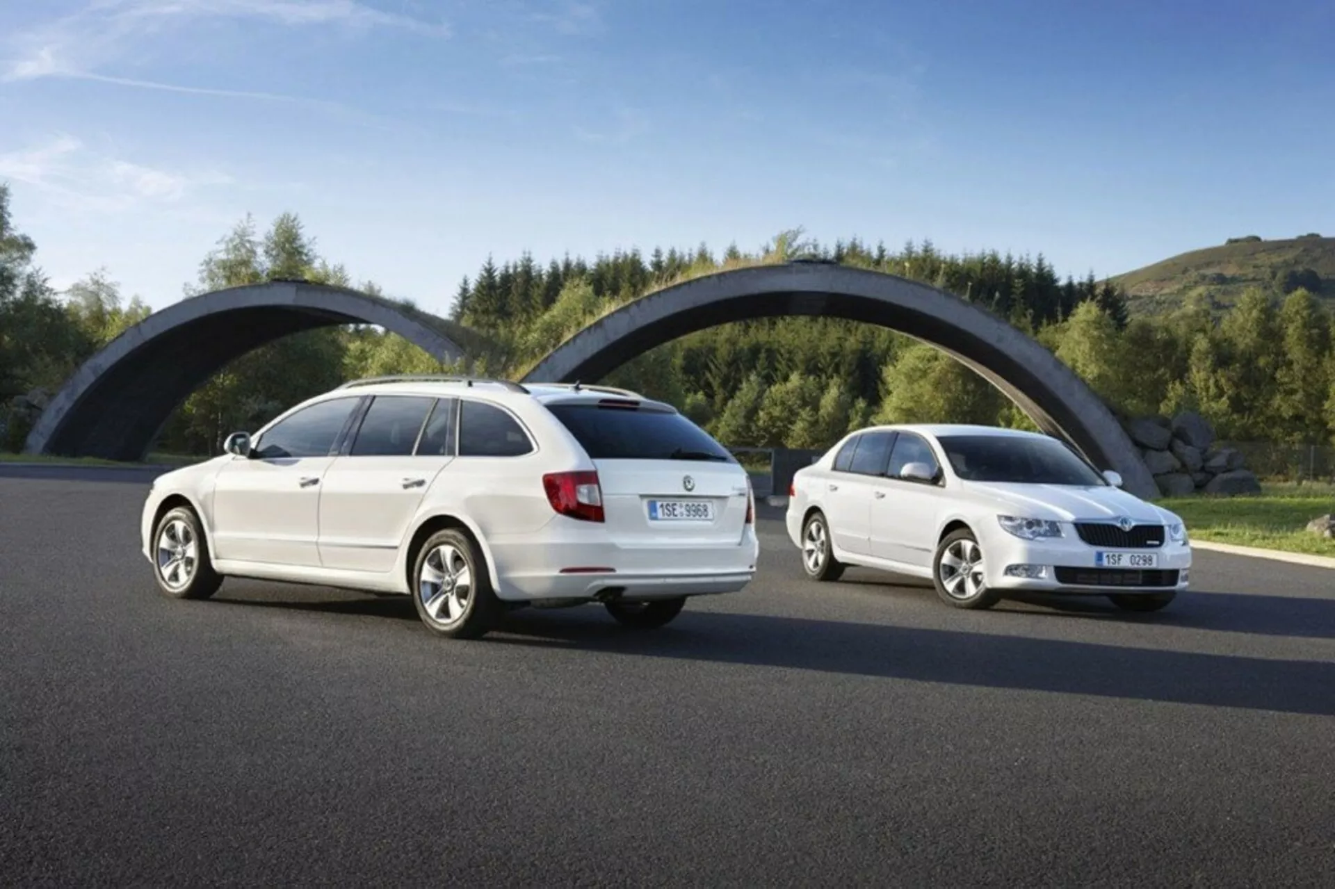 Skoda Superb break de 2008 en plein jour, présentant des angles arrière et avant de trois quarts sur une route en asphalte contre verdure et un pont courbé, se concentrant sur des éléments de design comme les feux arrière, la calandre avant et la silhouette du véhicule.