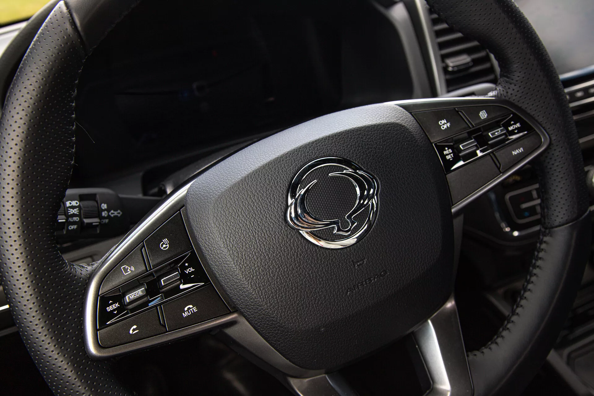 Vue rapprochée du volant du SsangYong Musso Grand 2022 avec enrobage en cuir, accents chromés et boutons de contrôle avancés