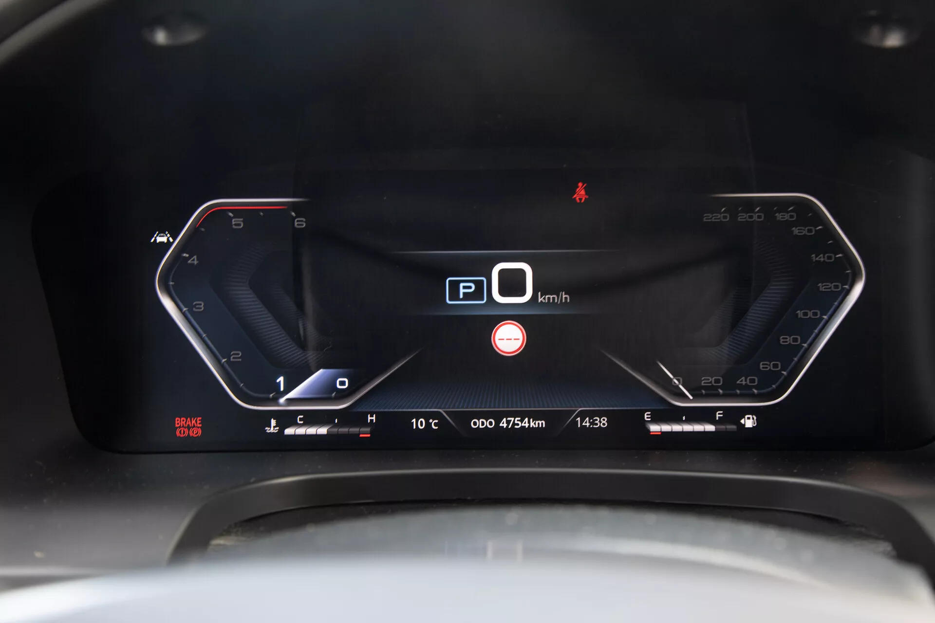 Gros plan sur le tableau de bord numérique du SsangYong Musso Grande pickup 2022 affichant un compteur de vitesse à 0 km/h, un indicateur de position de parking, et des fonctionnalités technologiques avancées