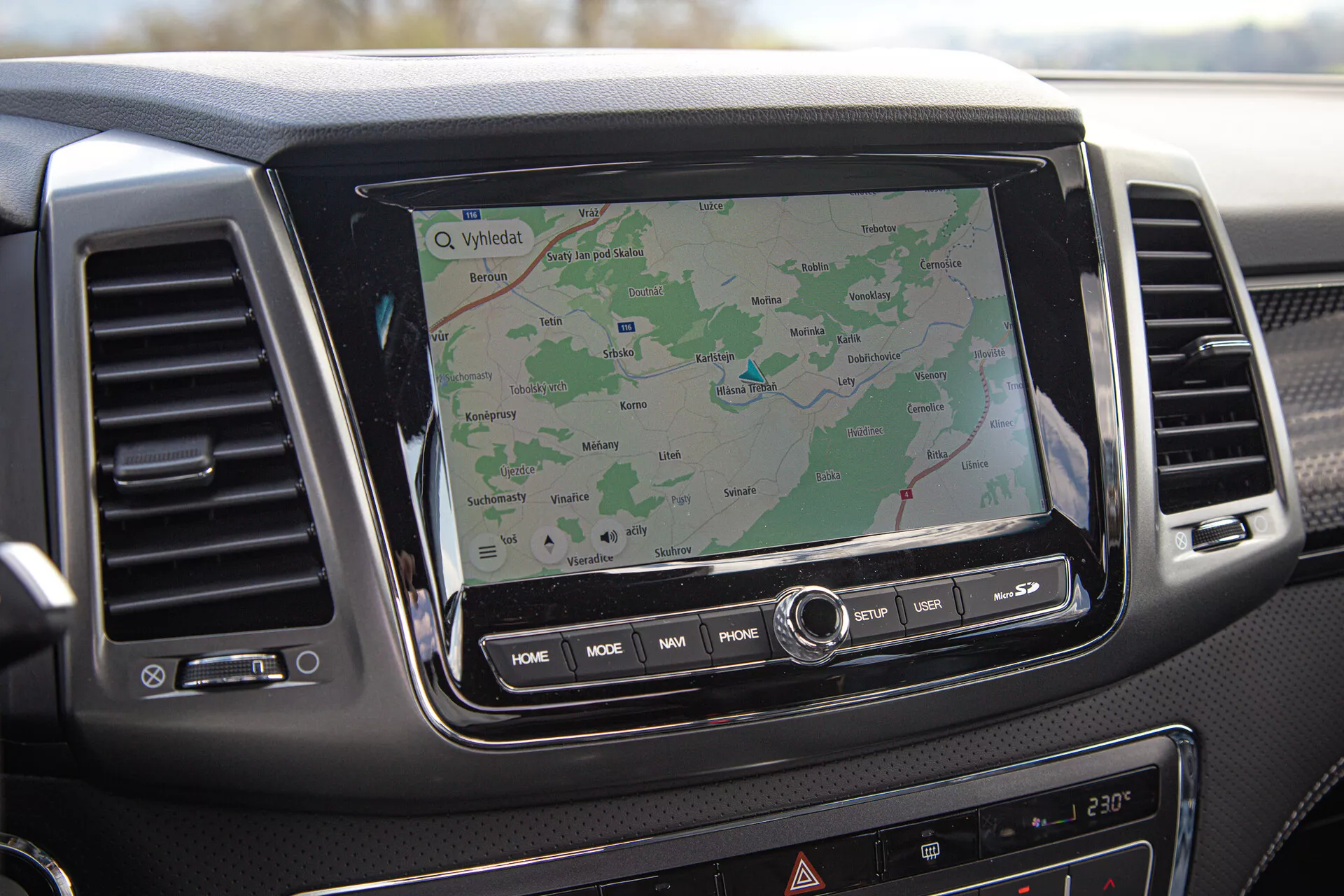 Tableau de bord du SsangYong Musso 2022 présentant le système d'infodivertissement tactile avec navigation GPS, bouches d'air et boutons de contrôle, vu de la perspective du passager.
