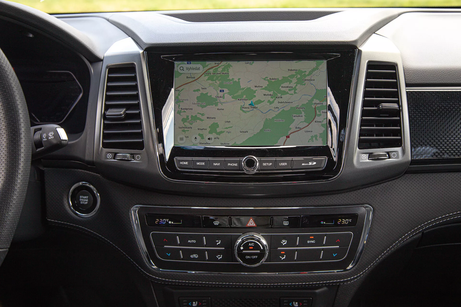 Tableau de bord du pick-up SsangYong Musso Grand 2022 doté d'un grand écran d'infodivertissement affichant la navigation, un système de climatisation bi-zone, une finition en matériel premium et divers boutons de contrôle