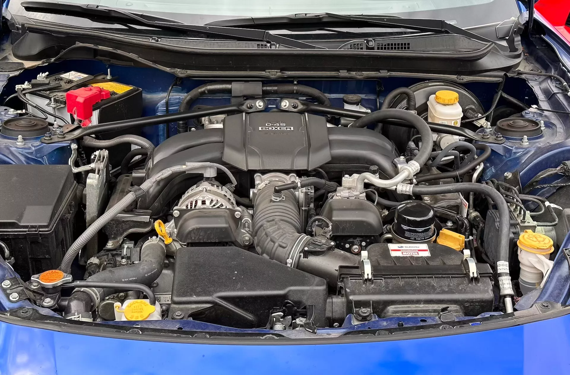 Vue détaillée du compartiment moteur de la Subaru BRZ 2023 avec moteur BOXER, batterie, réservoirs de fluide et système d'admission d'air visibles