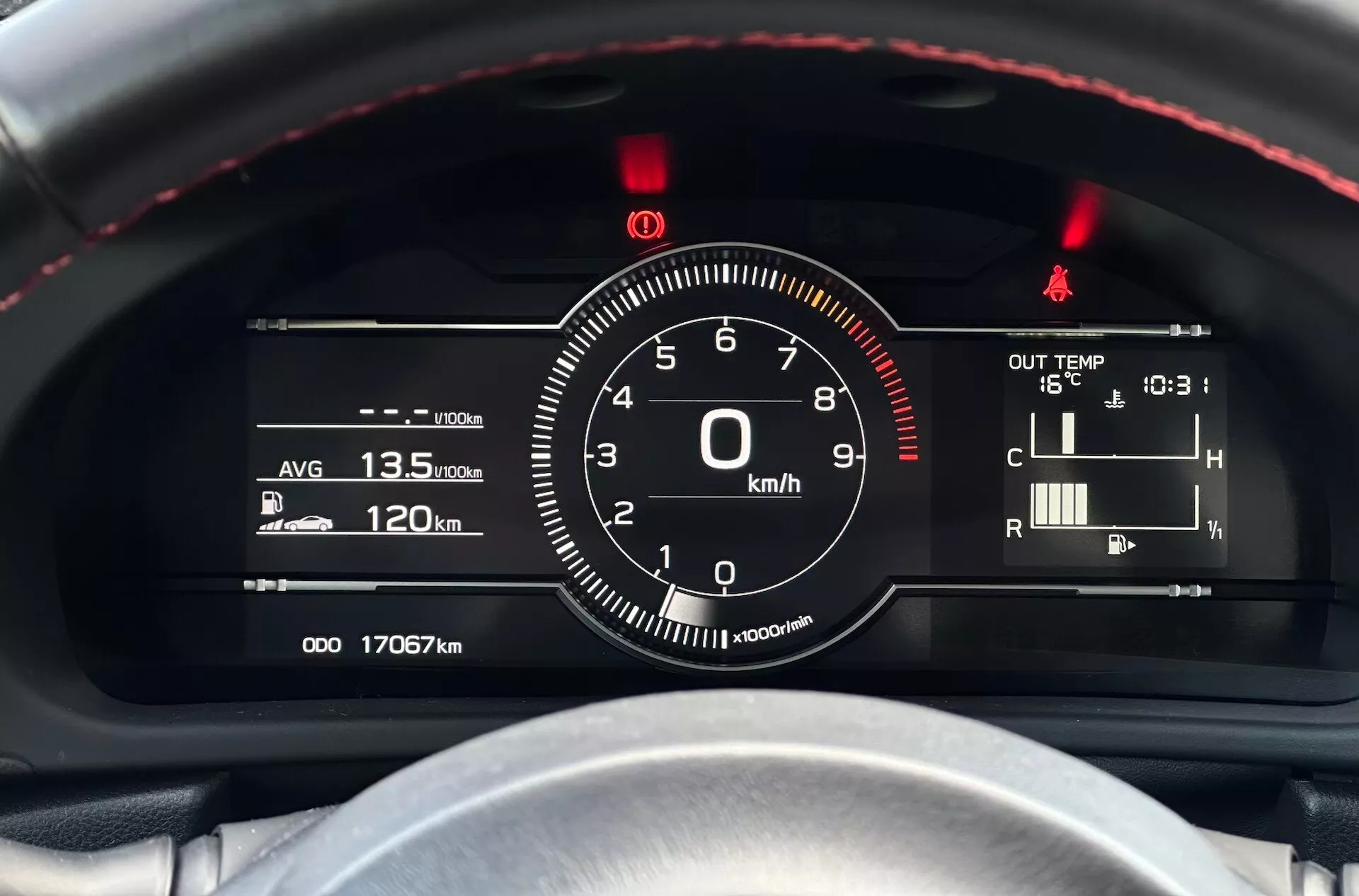 Vue détaillée du tableau de bord de la Subaru BRZ 2023 avec un focus sur le compteur de vitesse et d'autres jauges du point de vue du conducteur, présentant un volant cousu de fils rouges, une combinaison de jauges numériques-analogiques et des indicateurs technologiques tels que l'efficacité du carburant, la température et les lectures de l'odomètre.