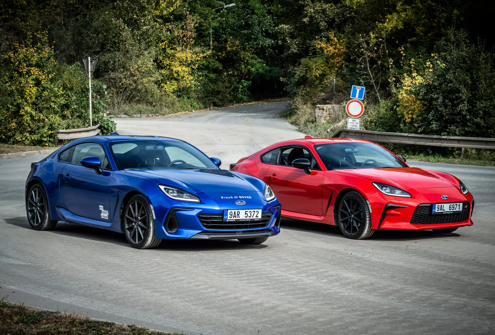 Coupés sportifs Subaru BRZ 2023 en bleu et rouge avec un design aérodynamique et des caractéristiques de performance, garés à l'extérieur entourés de feuillage naturel