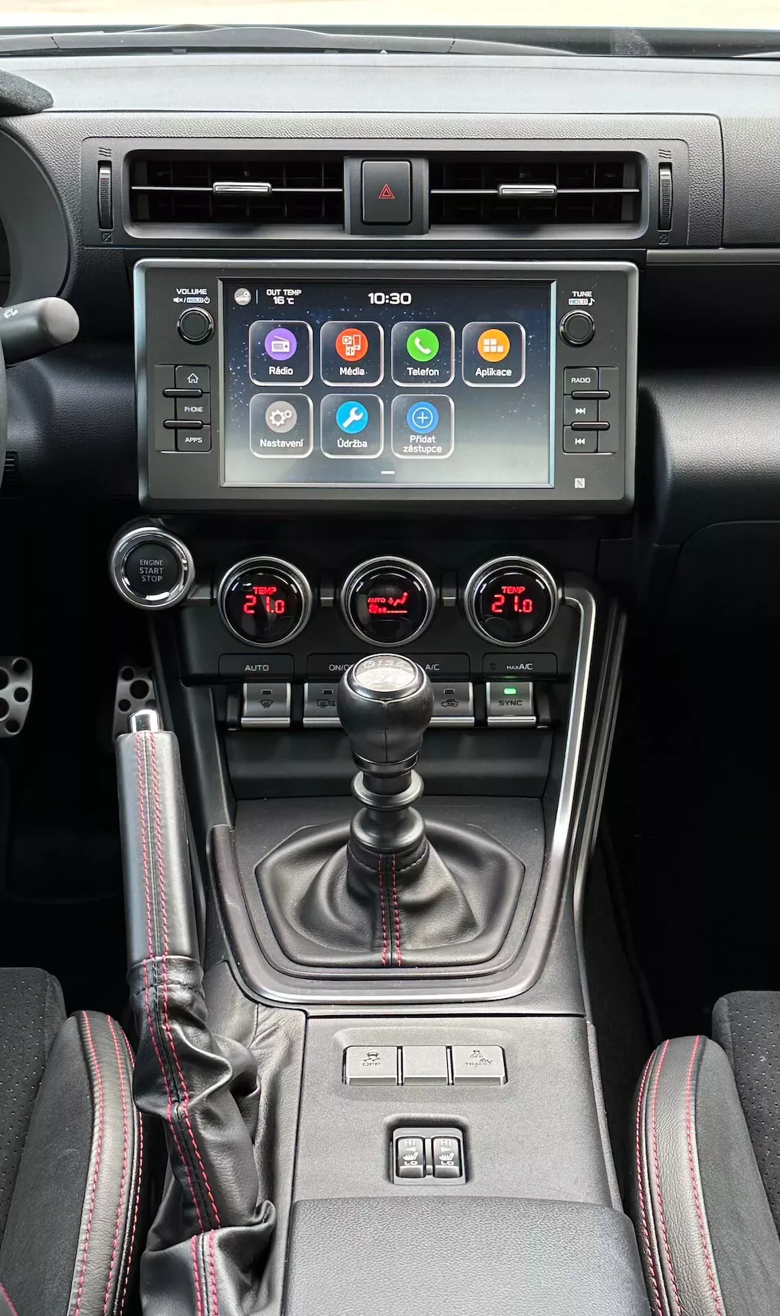 Intérieur du Subaru BRZ 2023 présentant la console centrale, mettant en vedette un écran tactile d'infodivertissement, indicateur de lumière de danger, bouches d'aération métalliques, contrôle climatique bi-zone, levier de vitesse manuel avec soufflet en cuir, commandes de chauffage de siège et un sélecteur de mode de conduite multi-mode dans un design moderne noir et métallique.