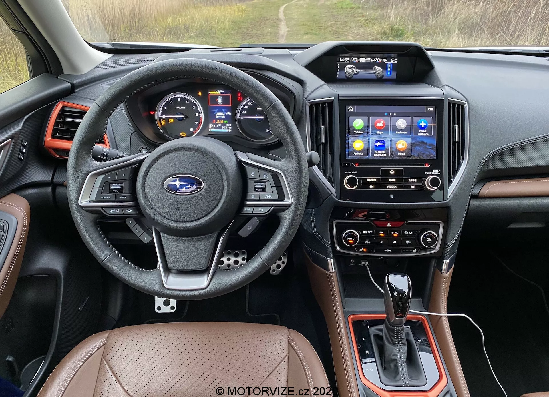 Vue intérieure depuis le siège du conducteur d'un Subaru Forester 2020, en se concentrant sur le tableau de bord, le volant, le système d'infodivertissement et la console centrale. Le volant en cuir à trois branches comprend des commandes multifonctions pour l'audio, le téléphone, les commandes vocales et le régulateur de vitesse, avec l'emblème Subaru centré. Le tableau de bord comprend un écran numérique et des jauges analogiques pour la vitesse et le régime. La console centrale abrite le levier de vitesses d'une transmission automatique, des commandes supplémentaires et un sélecteur de mode de conduite potentiel. L'écran tactile d'infodivertissement avec diverses icônes d'applications offre la navigation, les médias, la connectivité téléphonique et les réglages du véhicule. En dessous, les commandes de climatisation suggèrent des réglages bi-zone pour le conducteur et le passager avant. Les finitions intérieures comprennent des sièges en cuir ou simili cuir, des composants en plastique noir et des accents métalliques. Les bouches d'aération encadrent le système d'infodivertissement et les bords du tableau de bord. Cette image se classe dans les catégories des intérieurs de voiture, de la technologie automobile, des tableaux de bord, des systèmes d'infodivertissement et des commandes de climatisation.