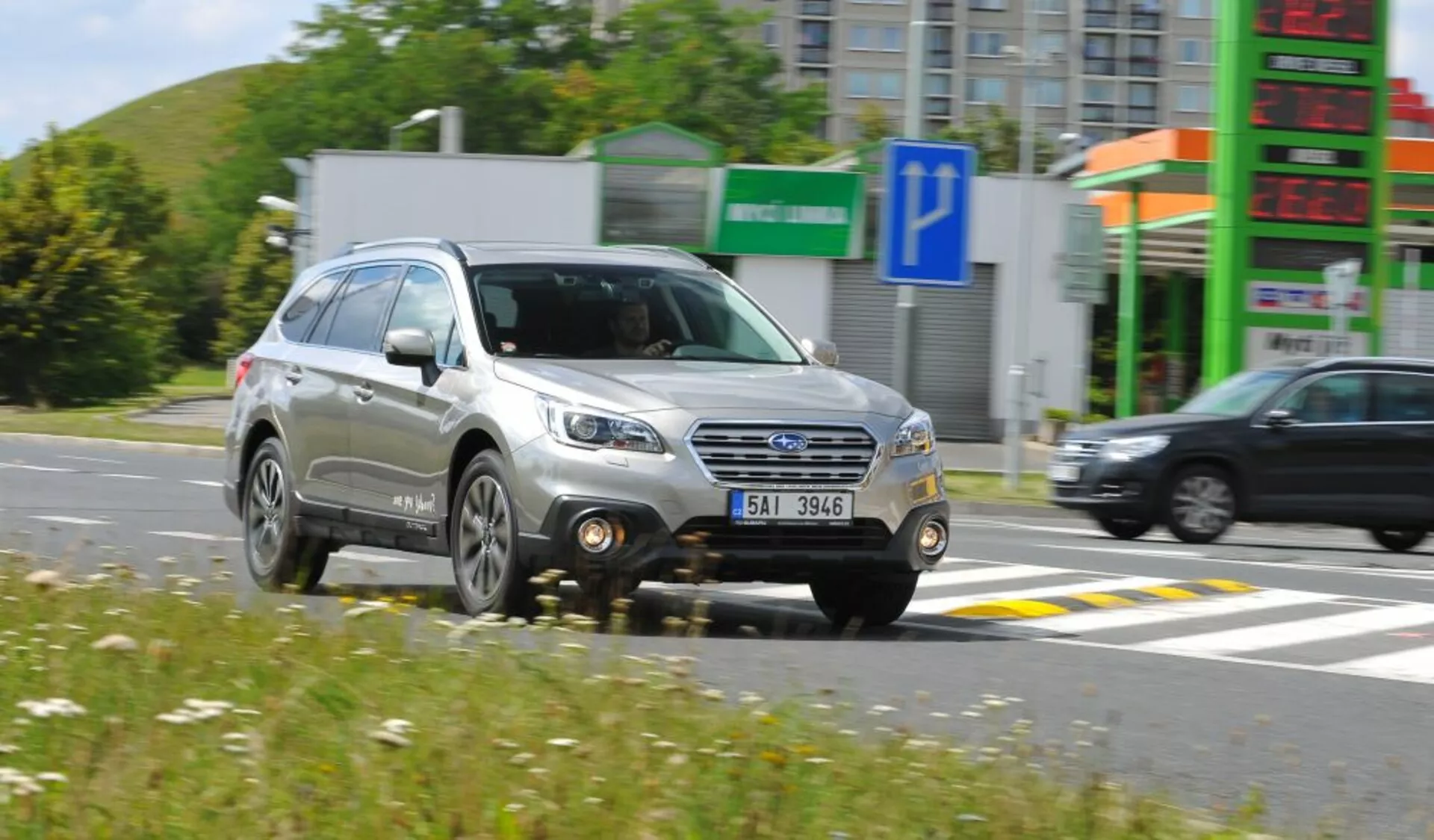 Subaru Outback de 2003 en mouvement, présentant une vue de trois quarts avant avec grille détaillée, phares et roues, soulignant son design de SUV compact et les caractéristiques utilitaires comme les barres de toit, sous un soleil éclatant.
