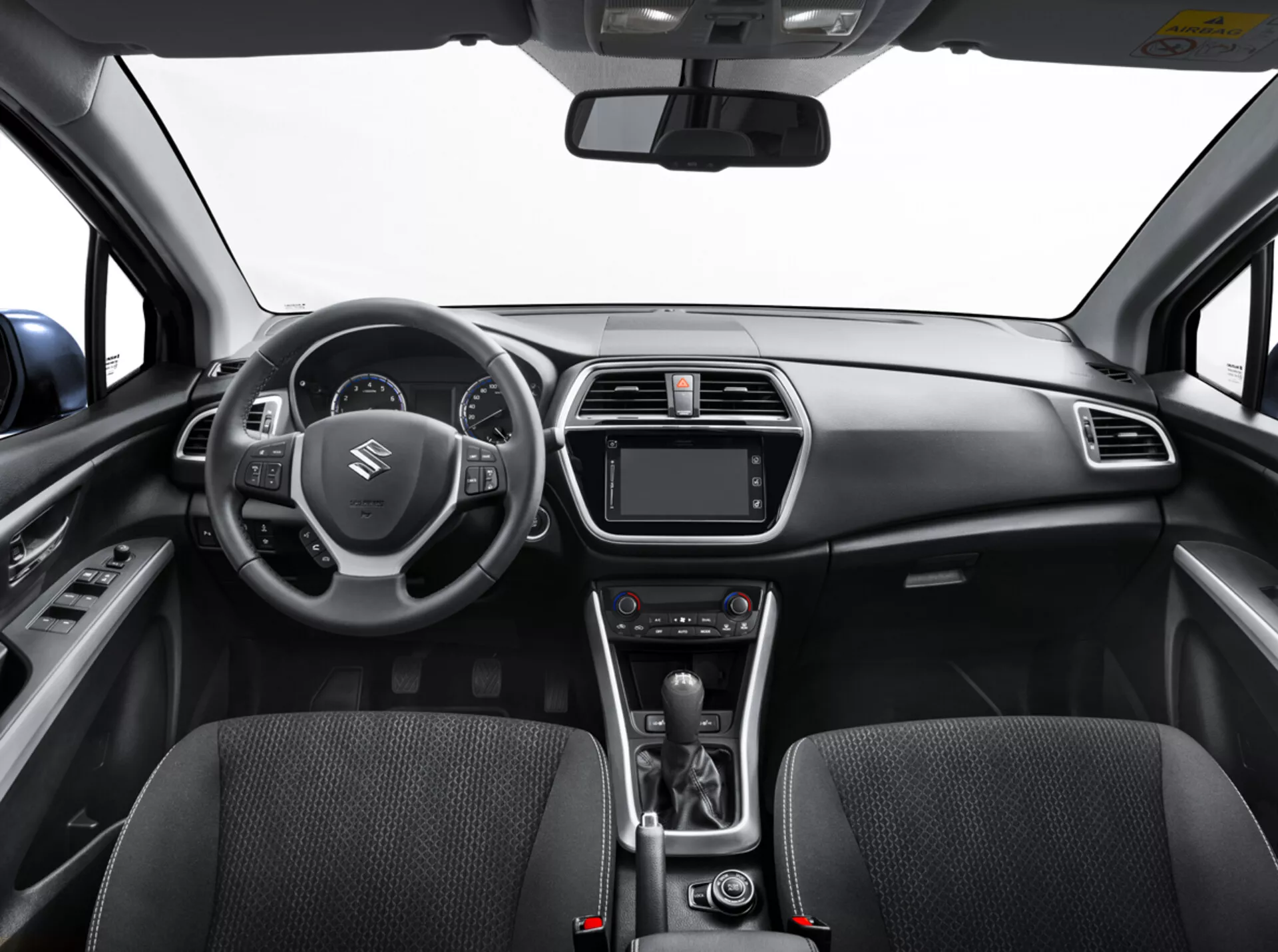 Vue intérieure du Suzuki S-Cross 2022 depuis le siège arrière montrant le tableau de bord, le volant avec commandes, le cluster d'instruments numériques, le système d'infodivertissement, les commandes de climatisation, le levier de vitesse automatique et les sièges avant détaillés avec une texture en tissu
