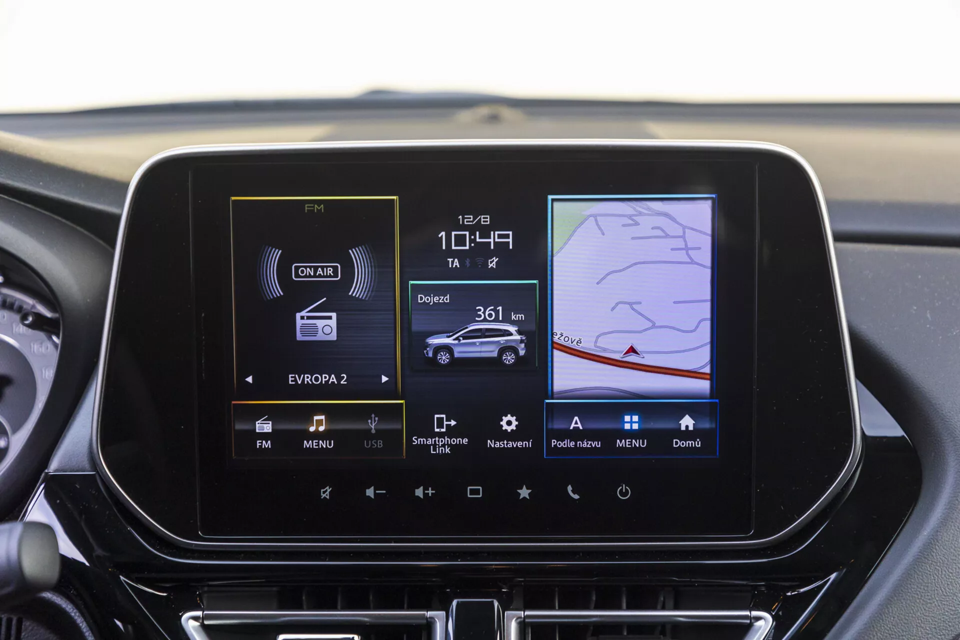 Tableau de bord central du Suzuki S-Cross 2022 présentant l'écran du système d'infodivertissement avec radio, contrôle climatique et fonctionnalités de navigation GPS